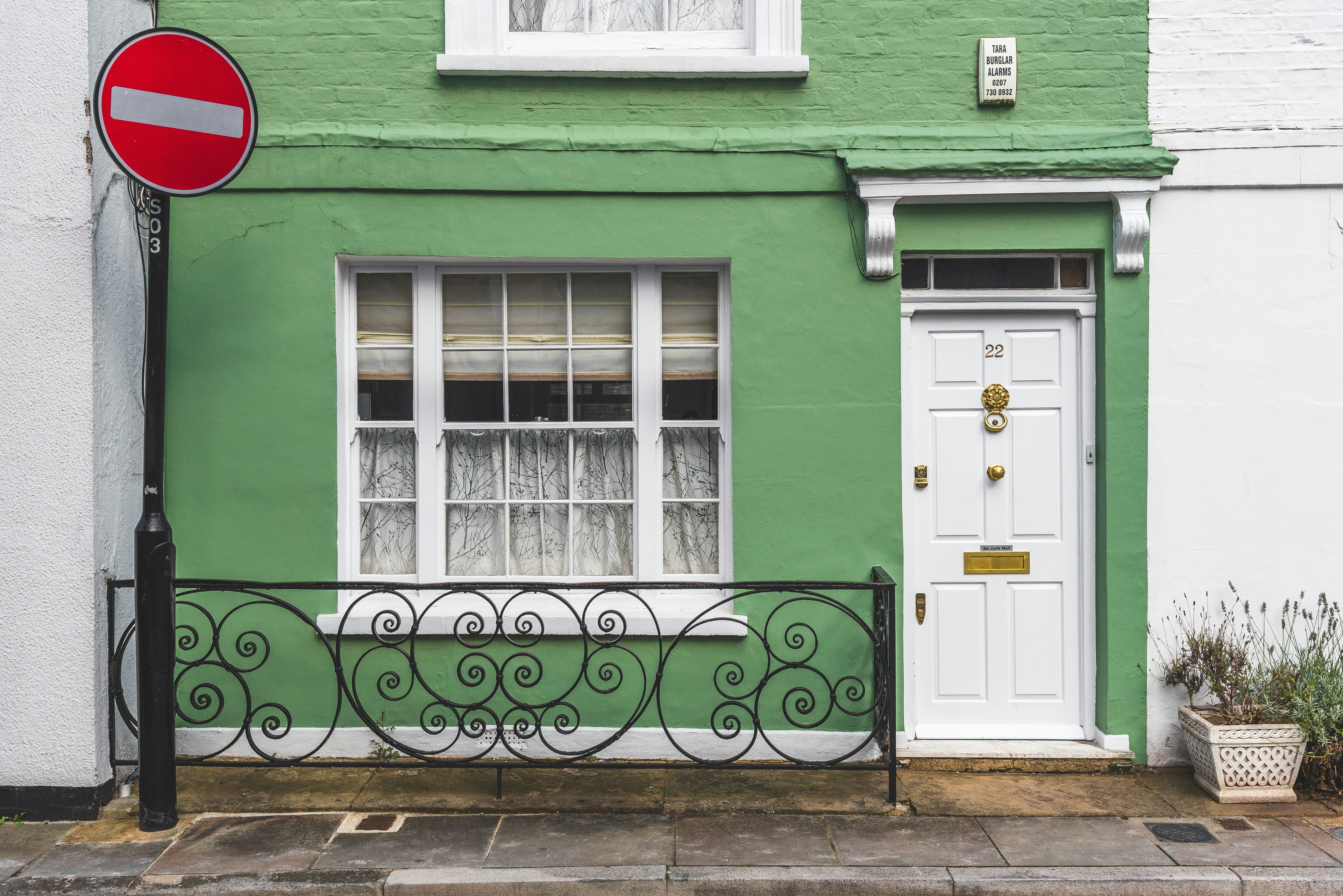 The front of a green-painted UK terraced house with a white panelled front door numbered 22.