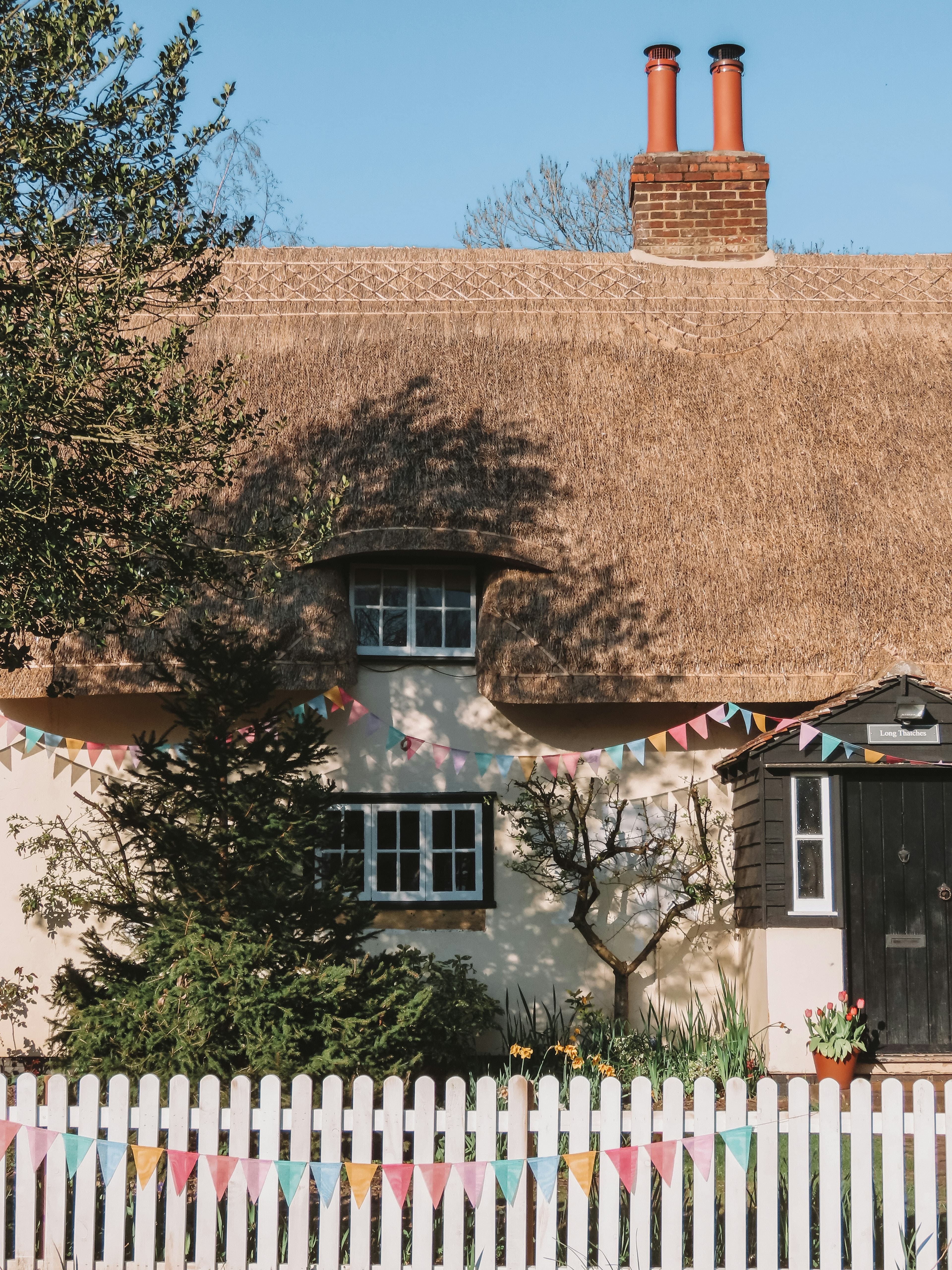 A brown and white residential house surrounded by green trees on a sunny day, representing typical Essex housing.
