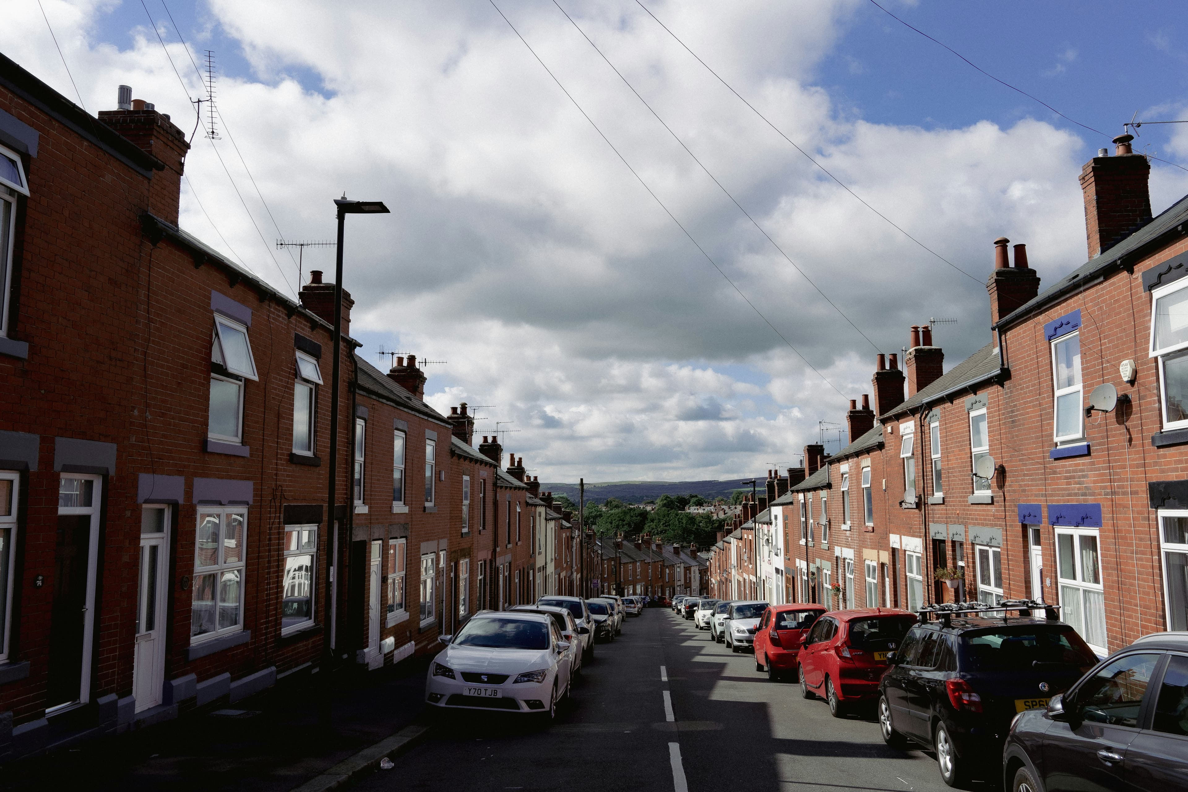 Cars parked along a street of brick terraced homes