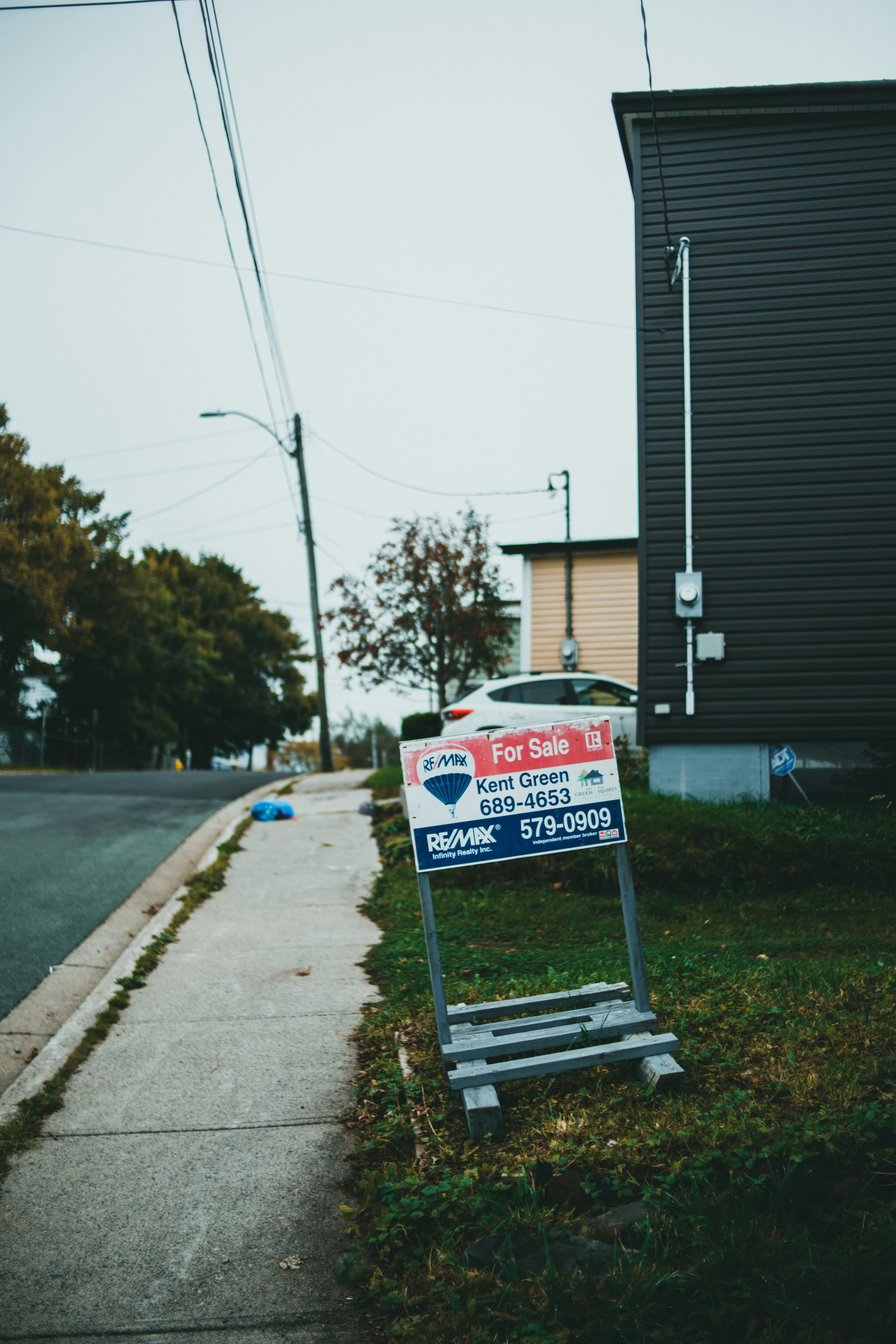An estate agent for-sale sign at the roadside outside a UK residential property