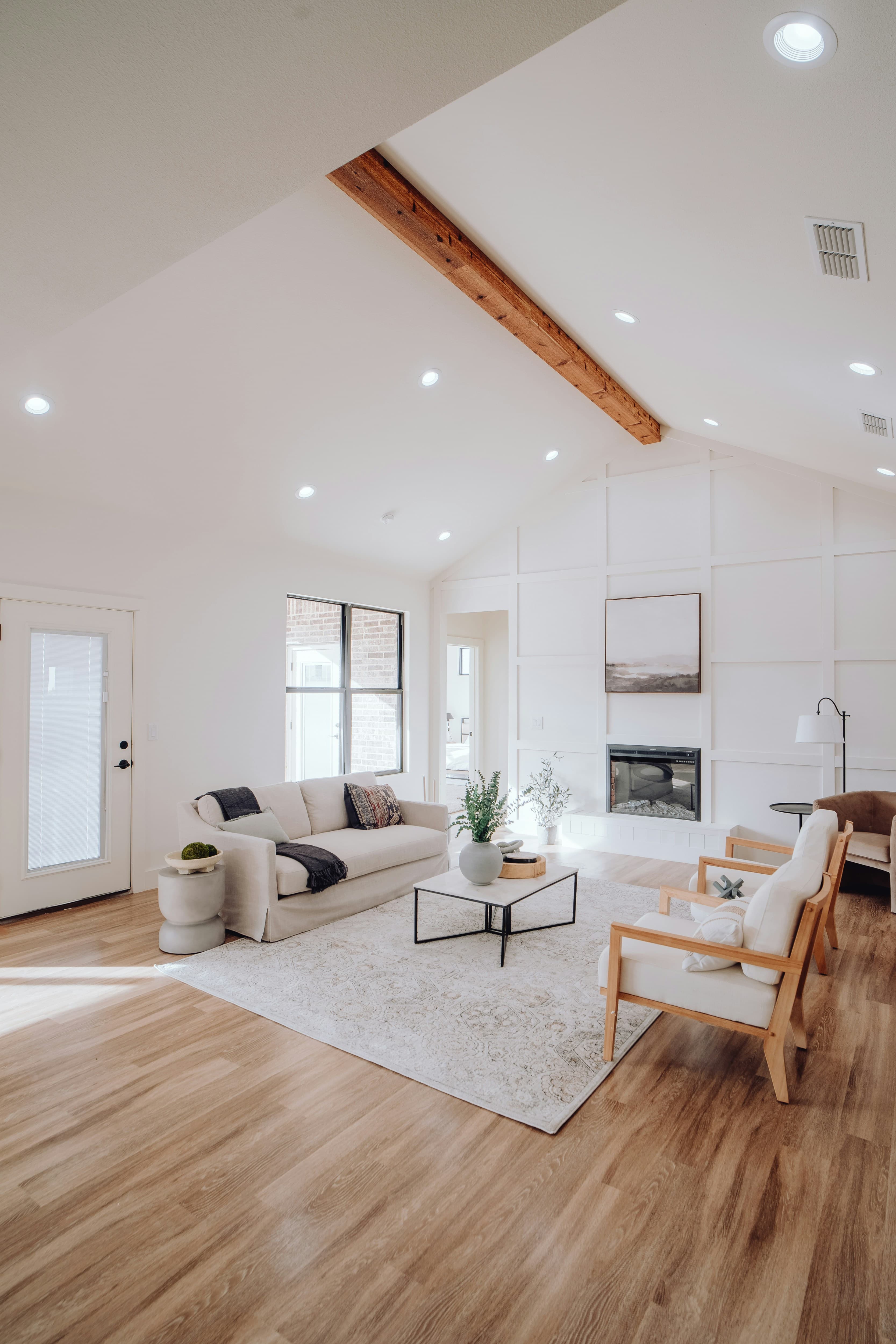 A tidy living room with a sofa, an armchair and a fireplace, ready for a visitor