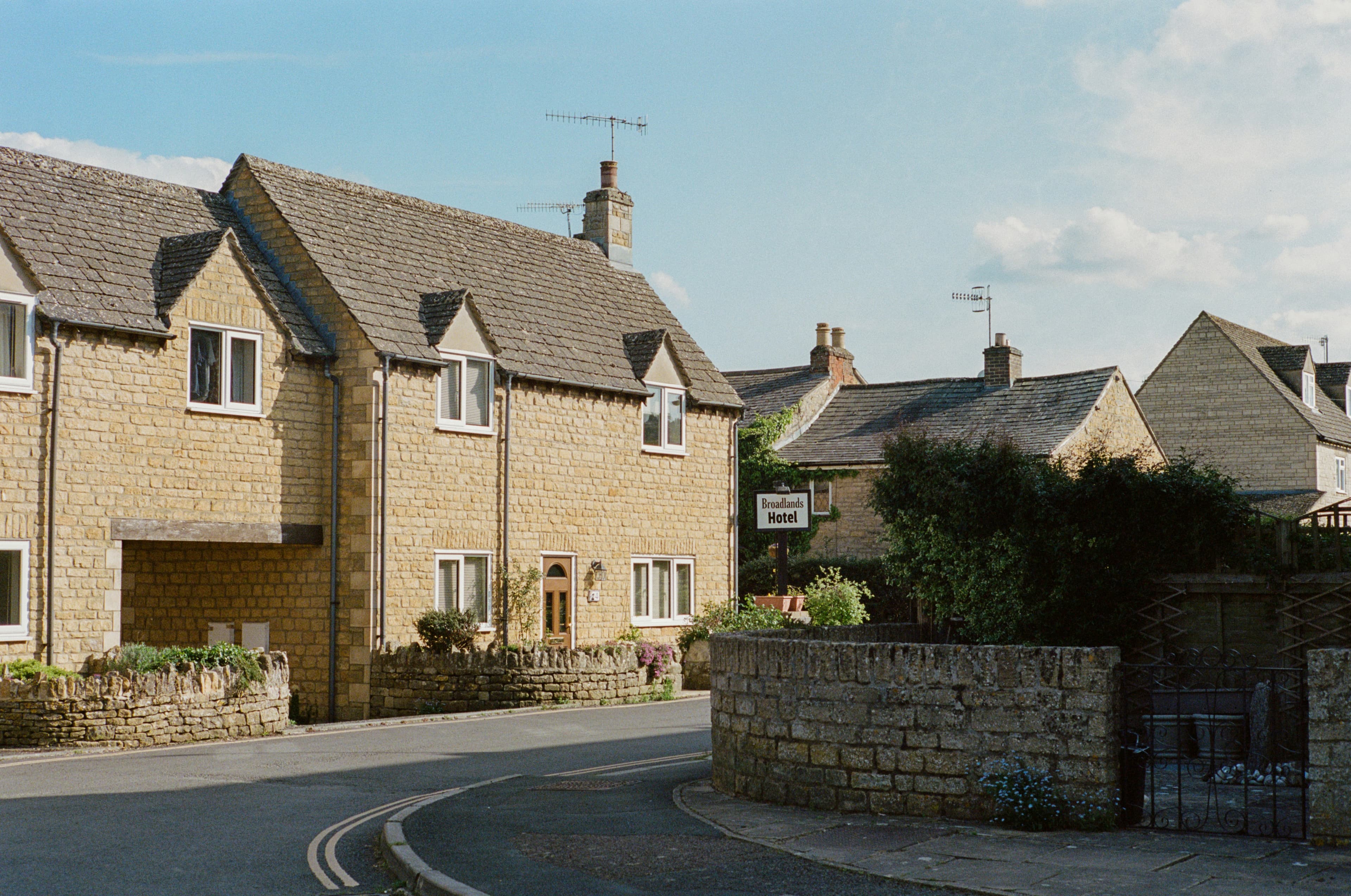 Stone-built houses on a curving residential street in an English town under a blue sky