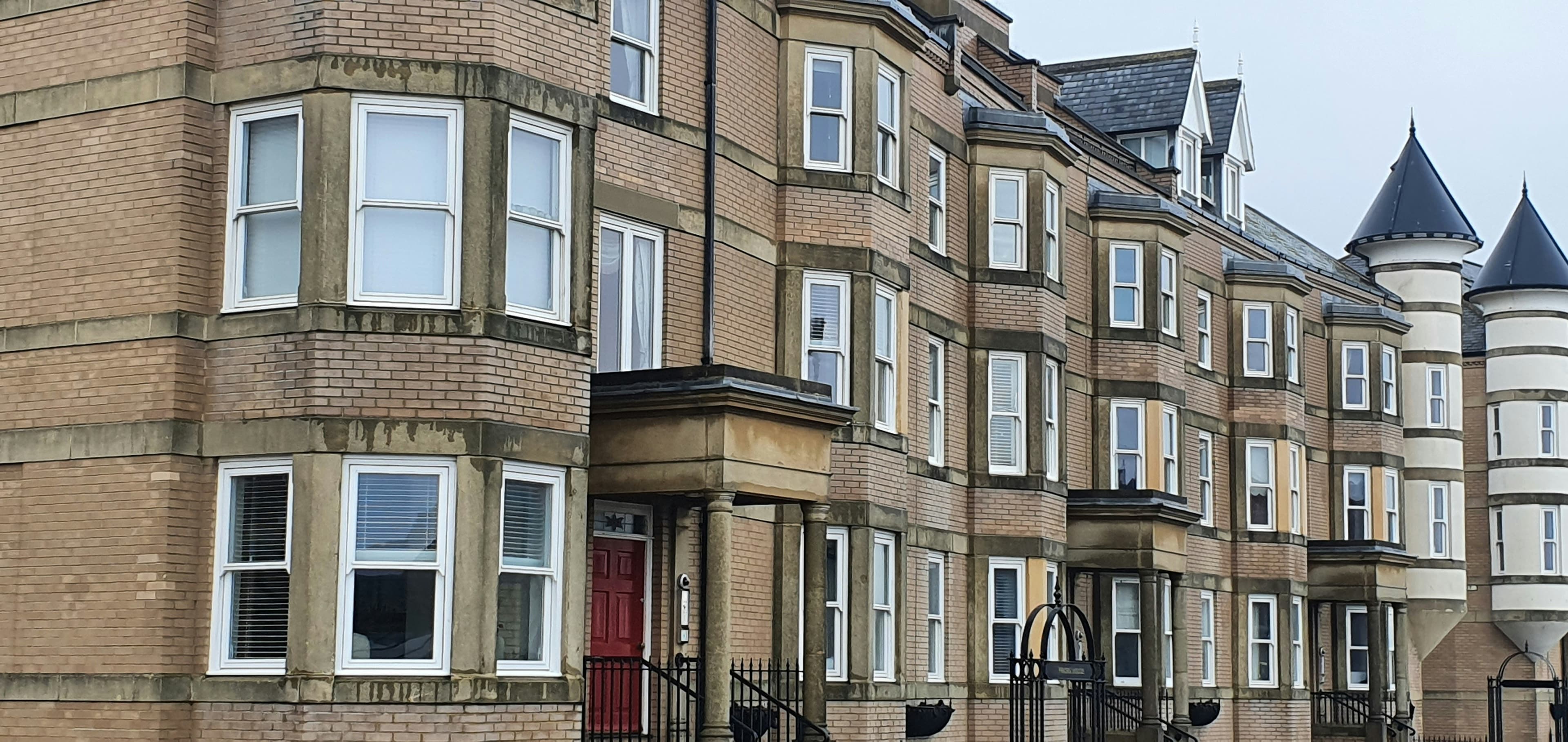 A row of near-identical brick terraced houses on a UK street