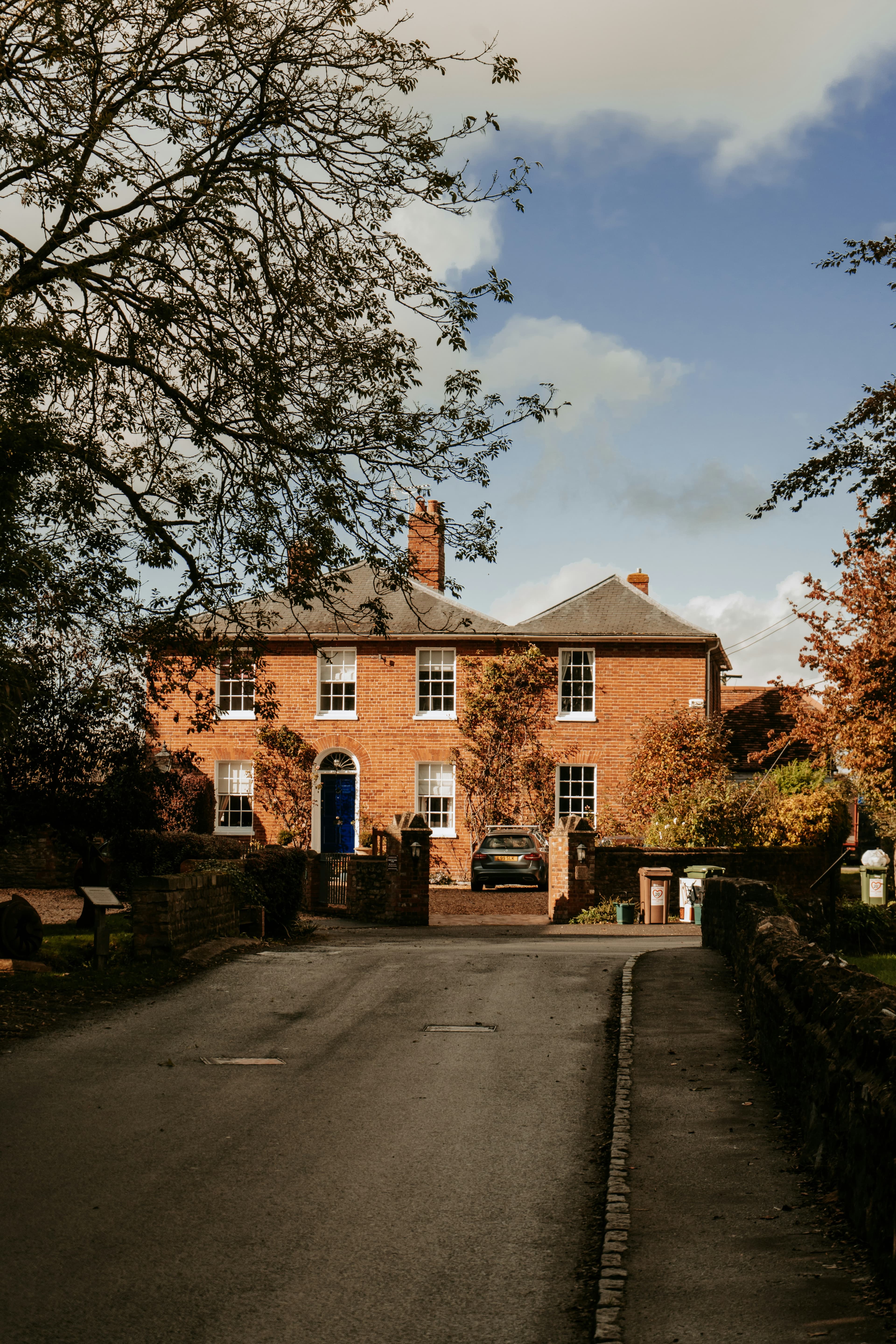 A traditional UK brick house with a navy blue front door on a quiet residential street
