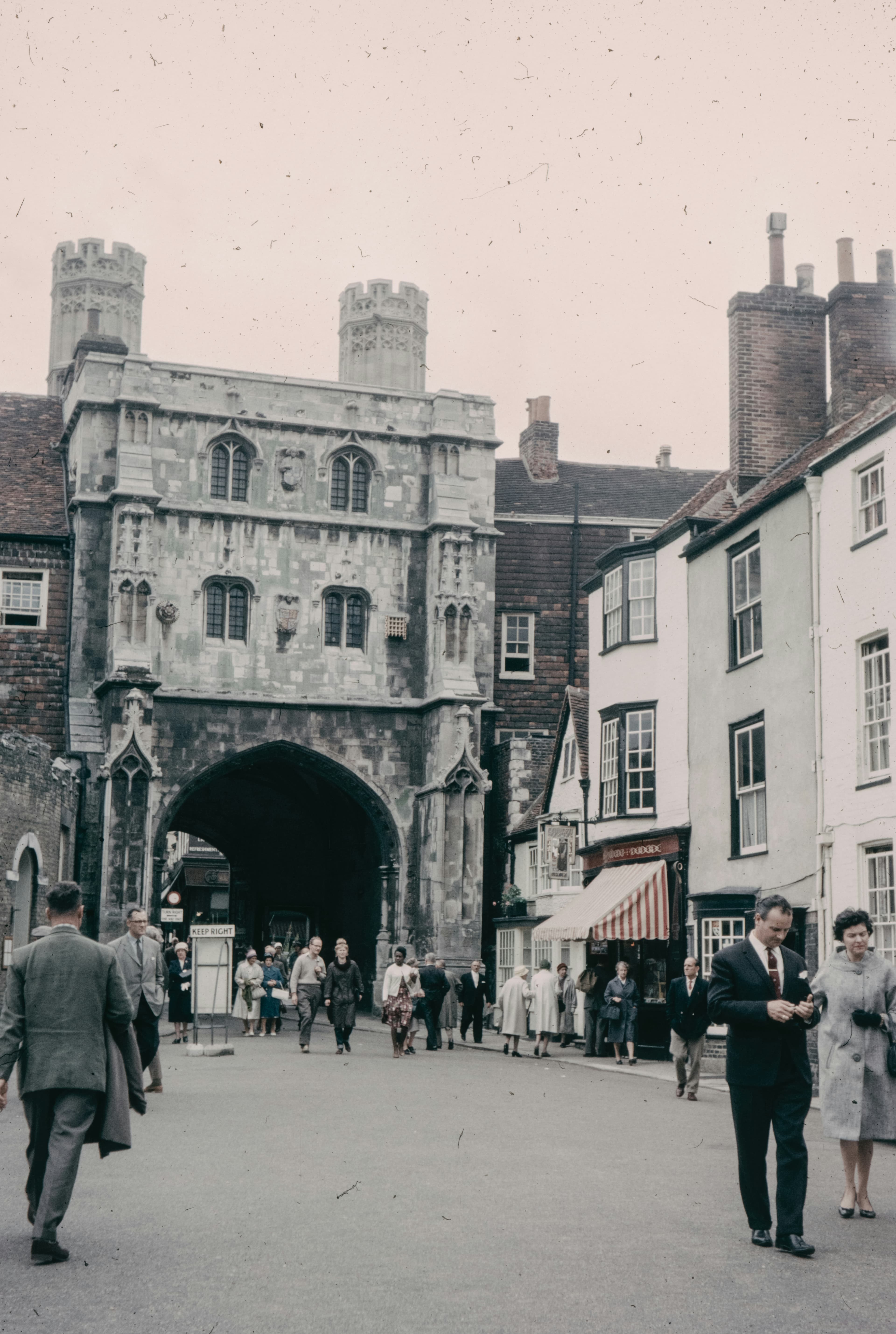 A vintage street scene of a post-war English town centre with pedestrians