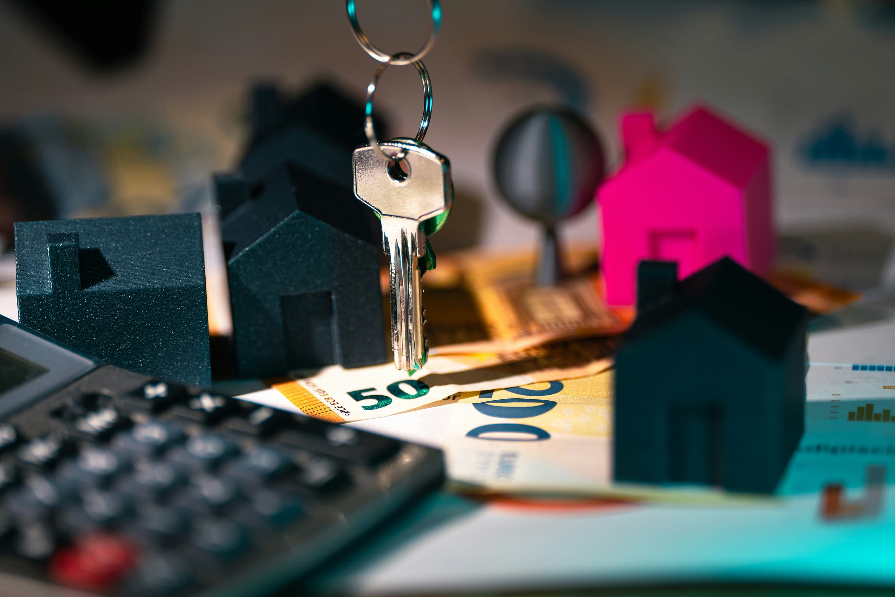 A calculator, a house-shaped keyring and a small model house on a table