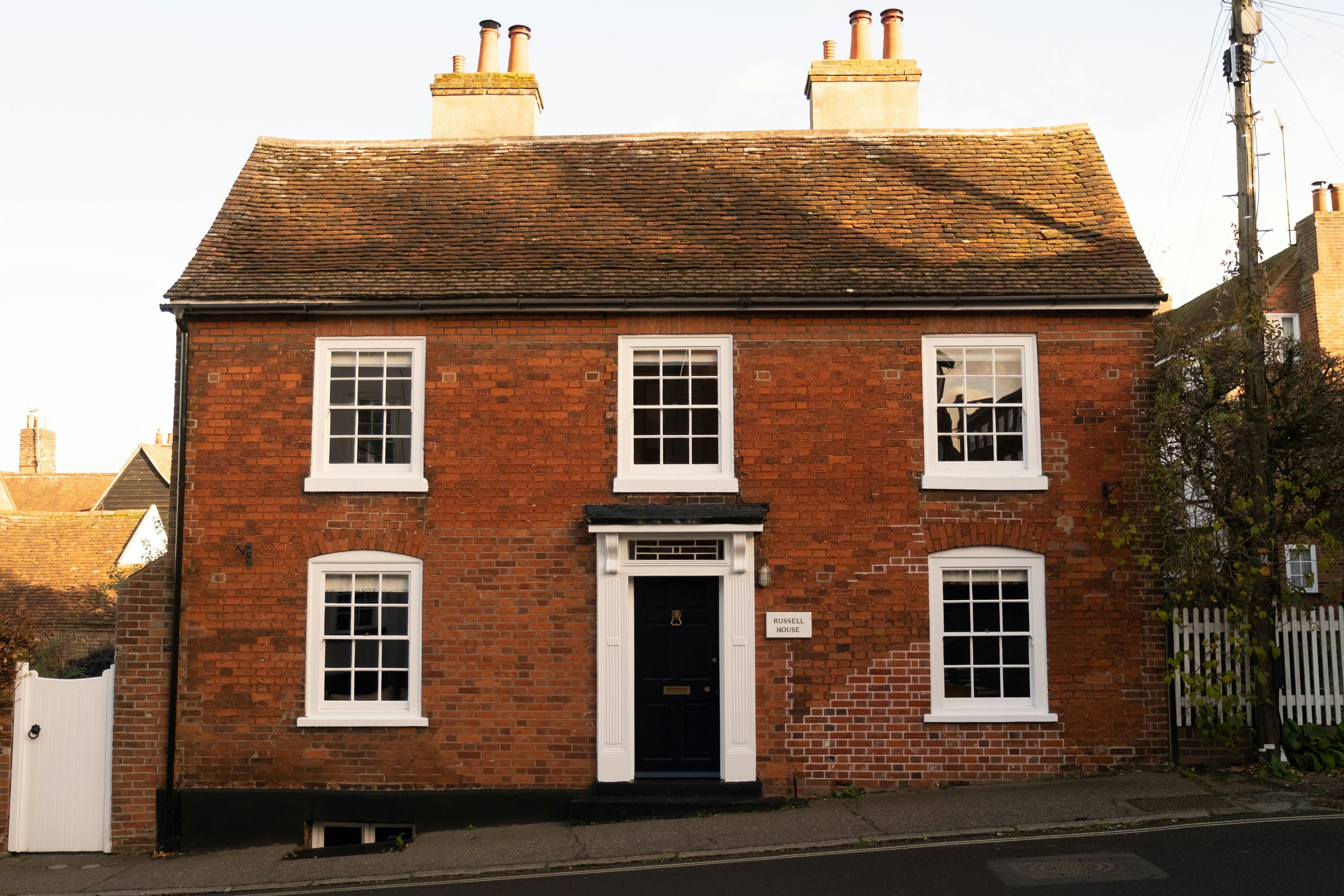 A red brick house with white windows and a black front door, a typical UK home for sale.