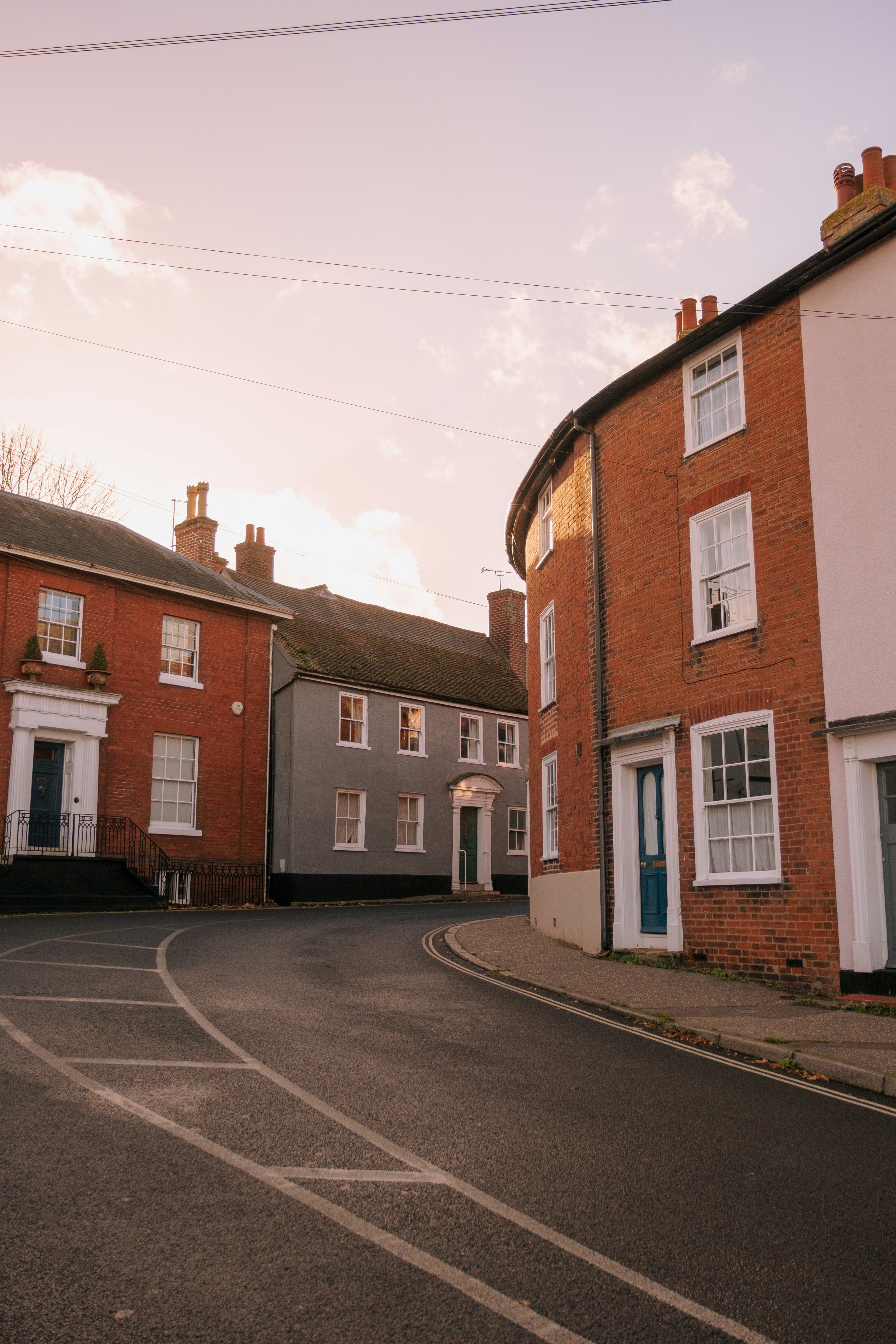 A row of linked brick terraced houses along a UK town street