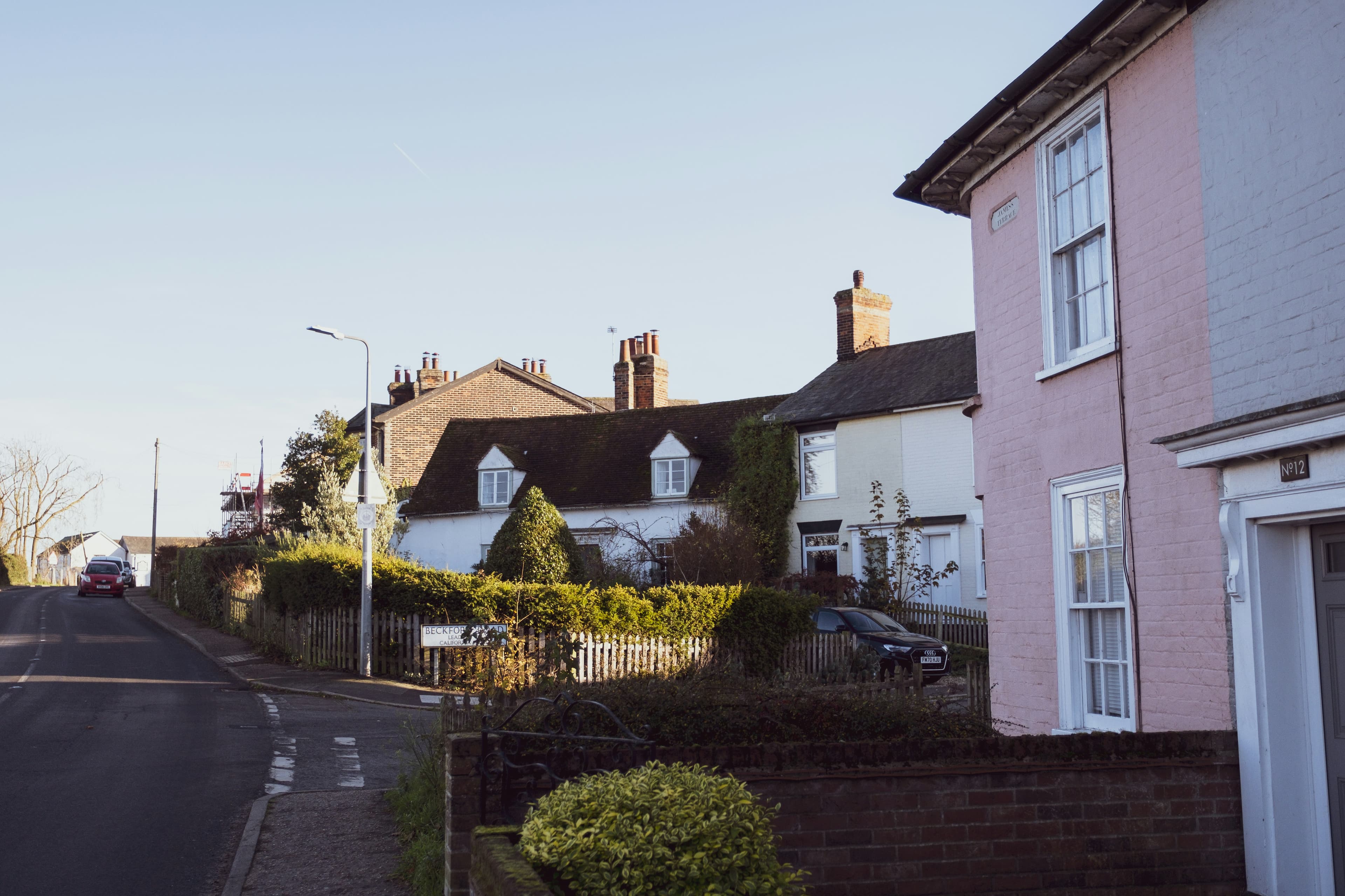 A quiet English residential street of brick and rendered houses with front gardens on a sunny winter afternoon