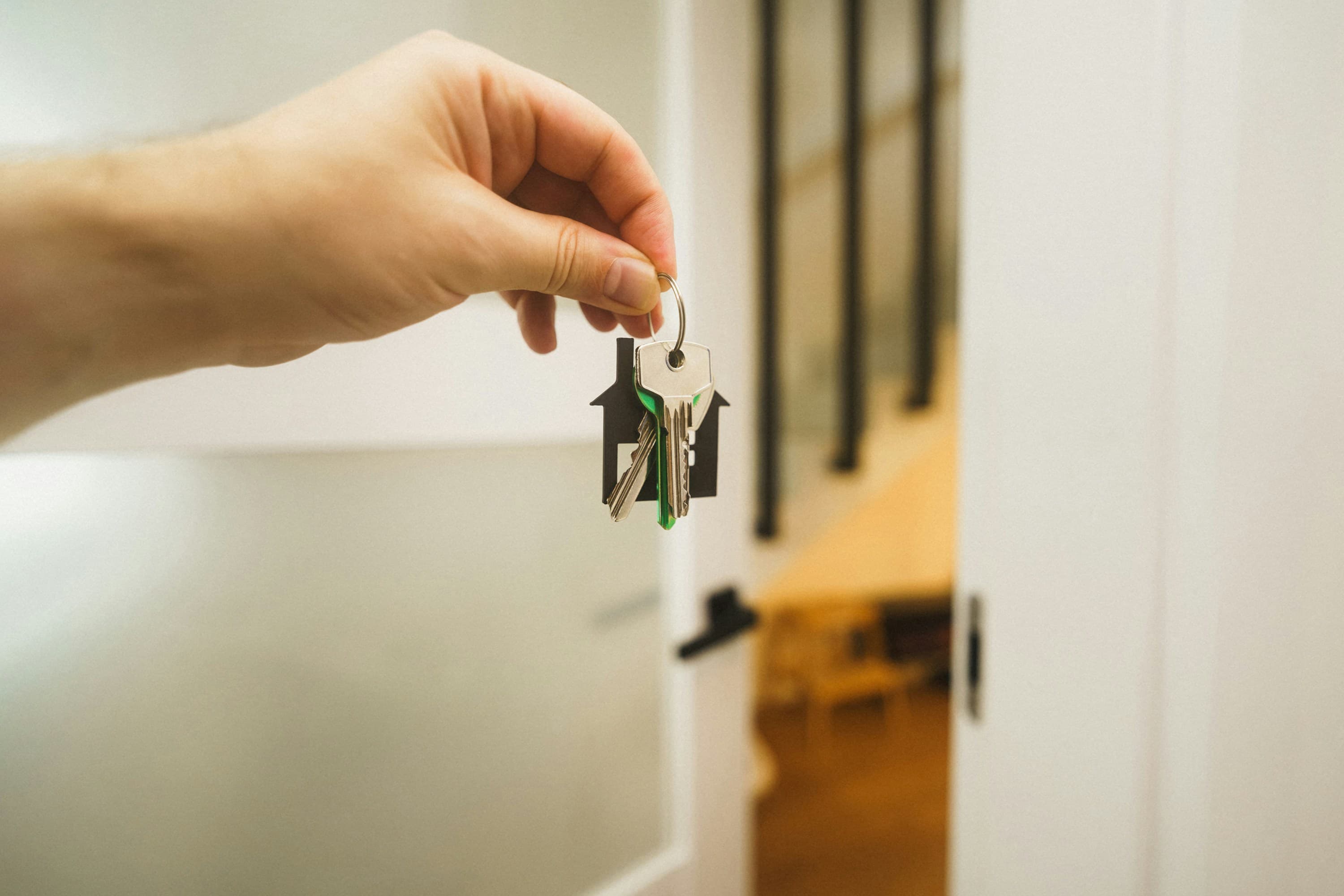 A person reading property paperwork at a table with a set of house keys nearby