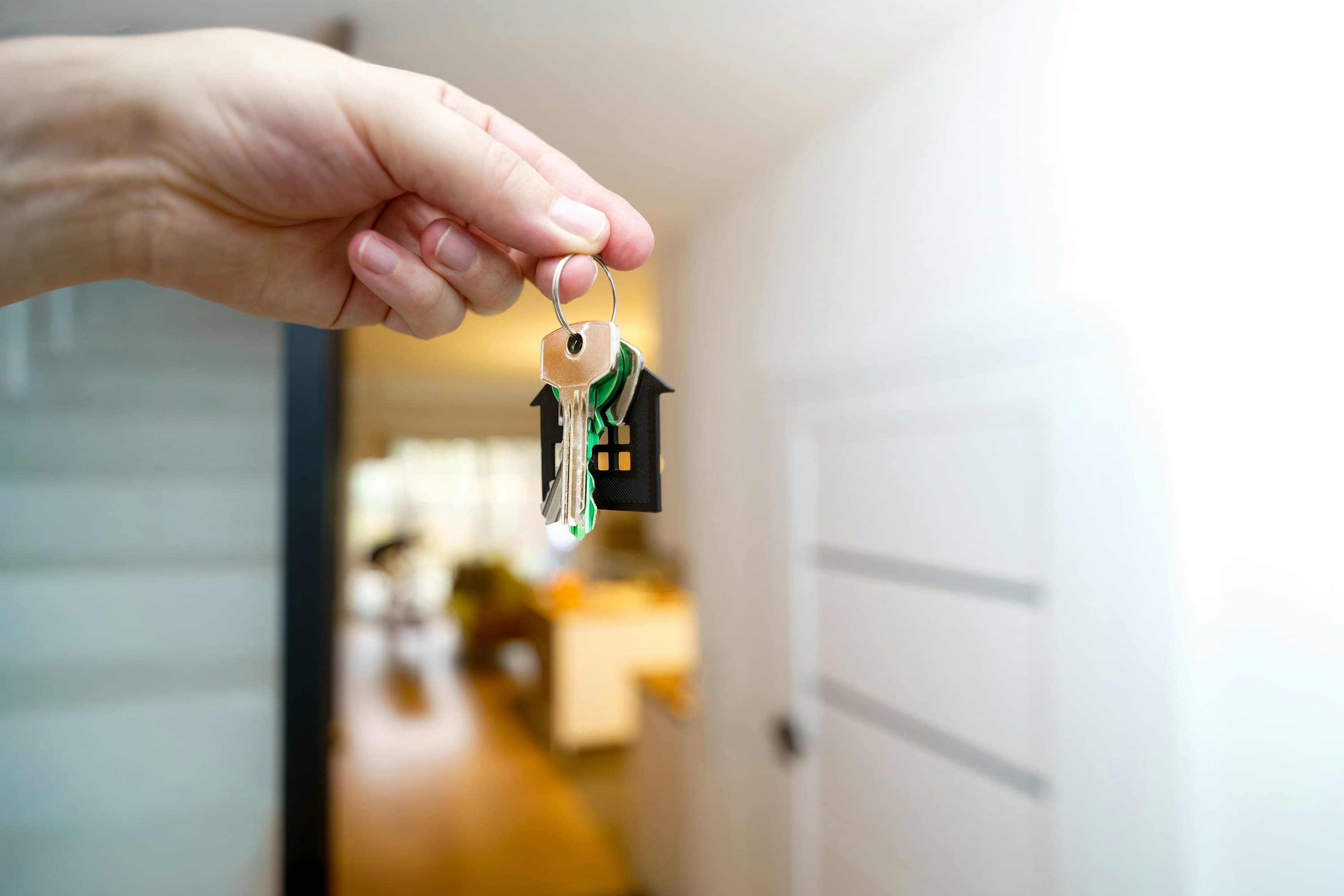 A hand holding a set of house keys, representing a homeowner moving to a new property.
