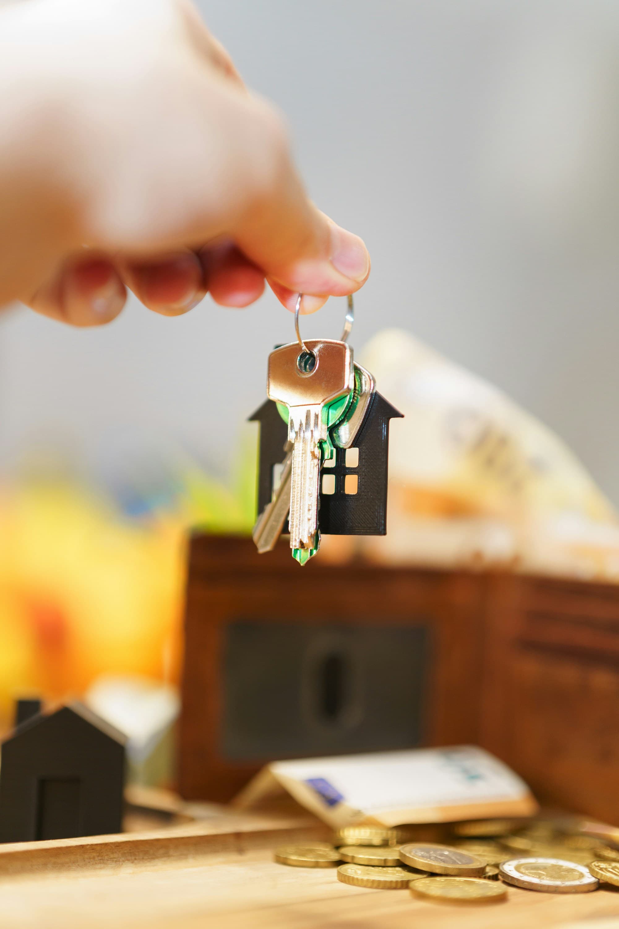 New house keys resting on banknotes and a wallet, representing the upfront cost of buying a first home.
