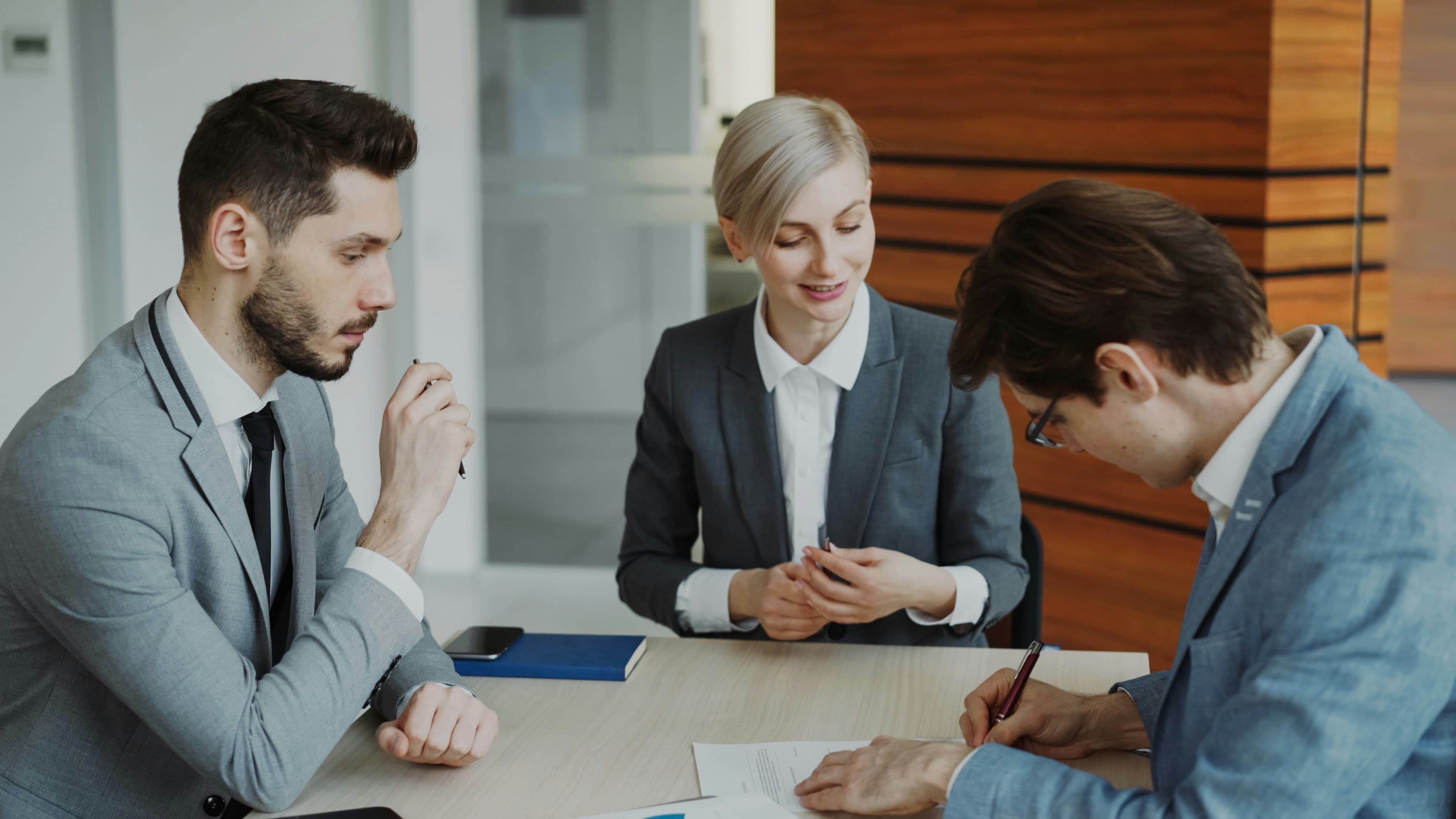 Two people signing property contracts at a table, representing exchange and completion when a house sale finishes