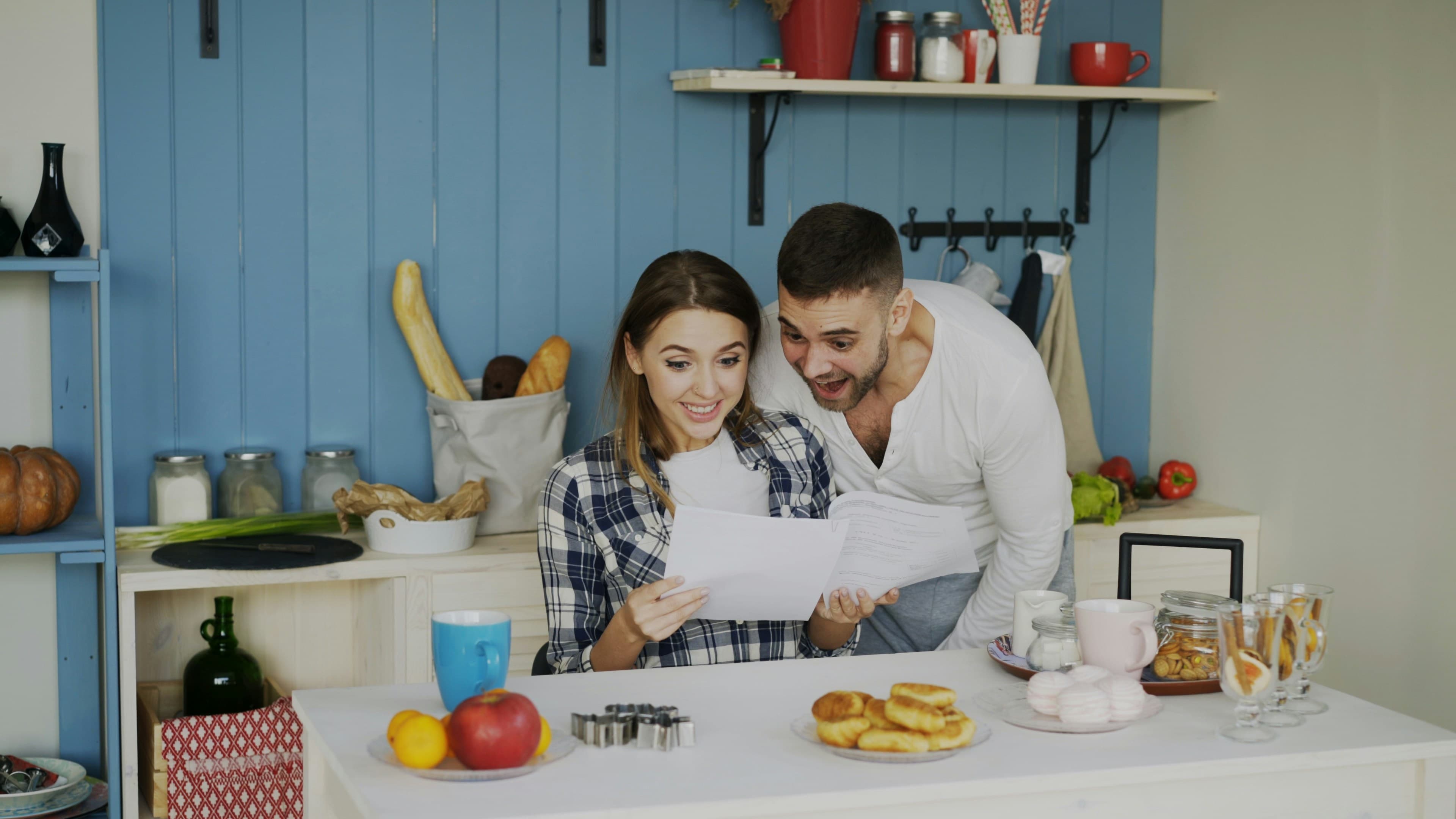 A couple looking through papers together at a table in a bright kitchen