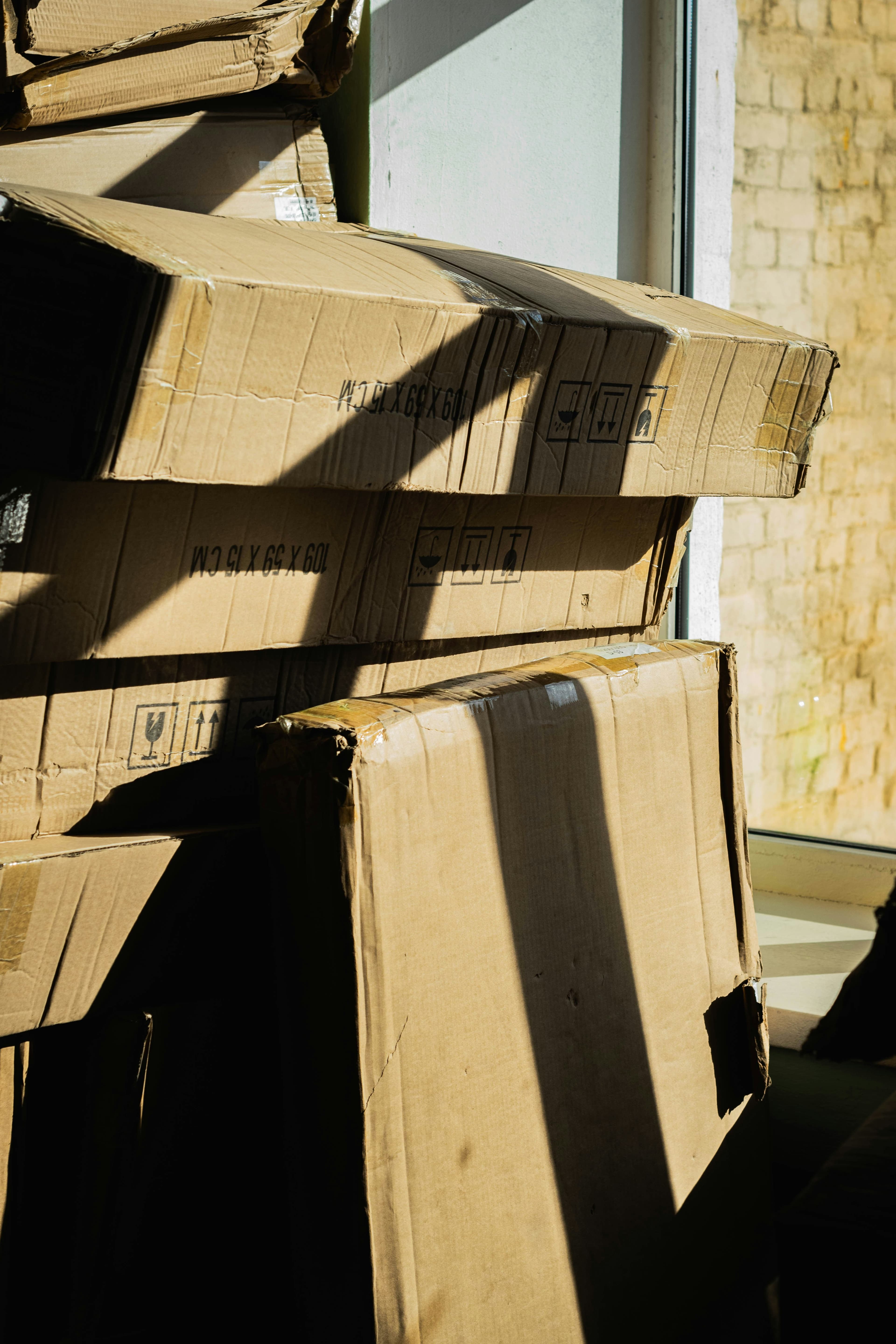 A stack of cardboard moving boxes beside a window in a quiet room