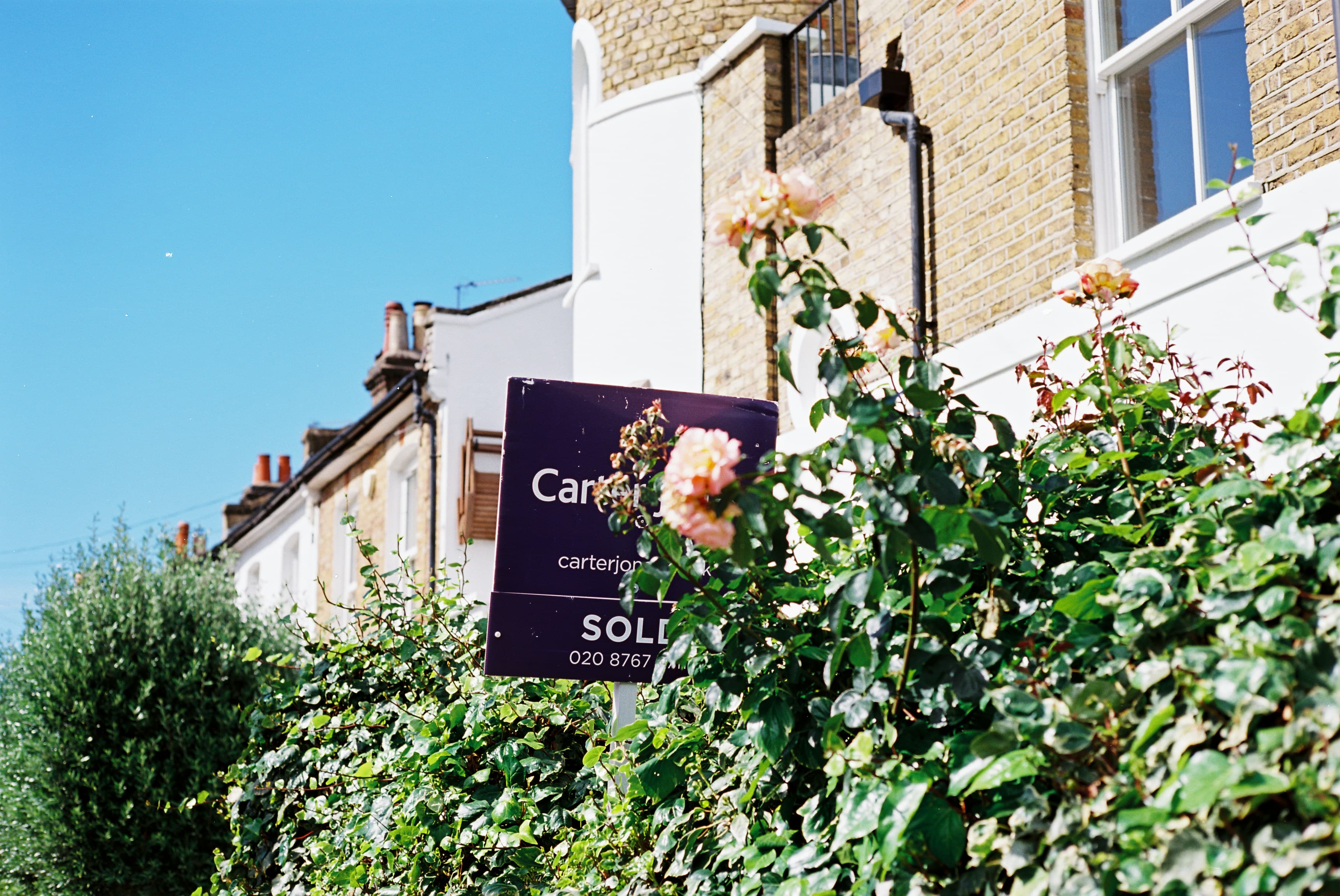 A sold sign and roses outside a house, marking a completed sale
