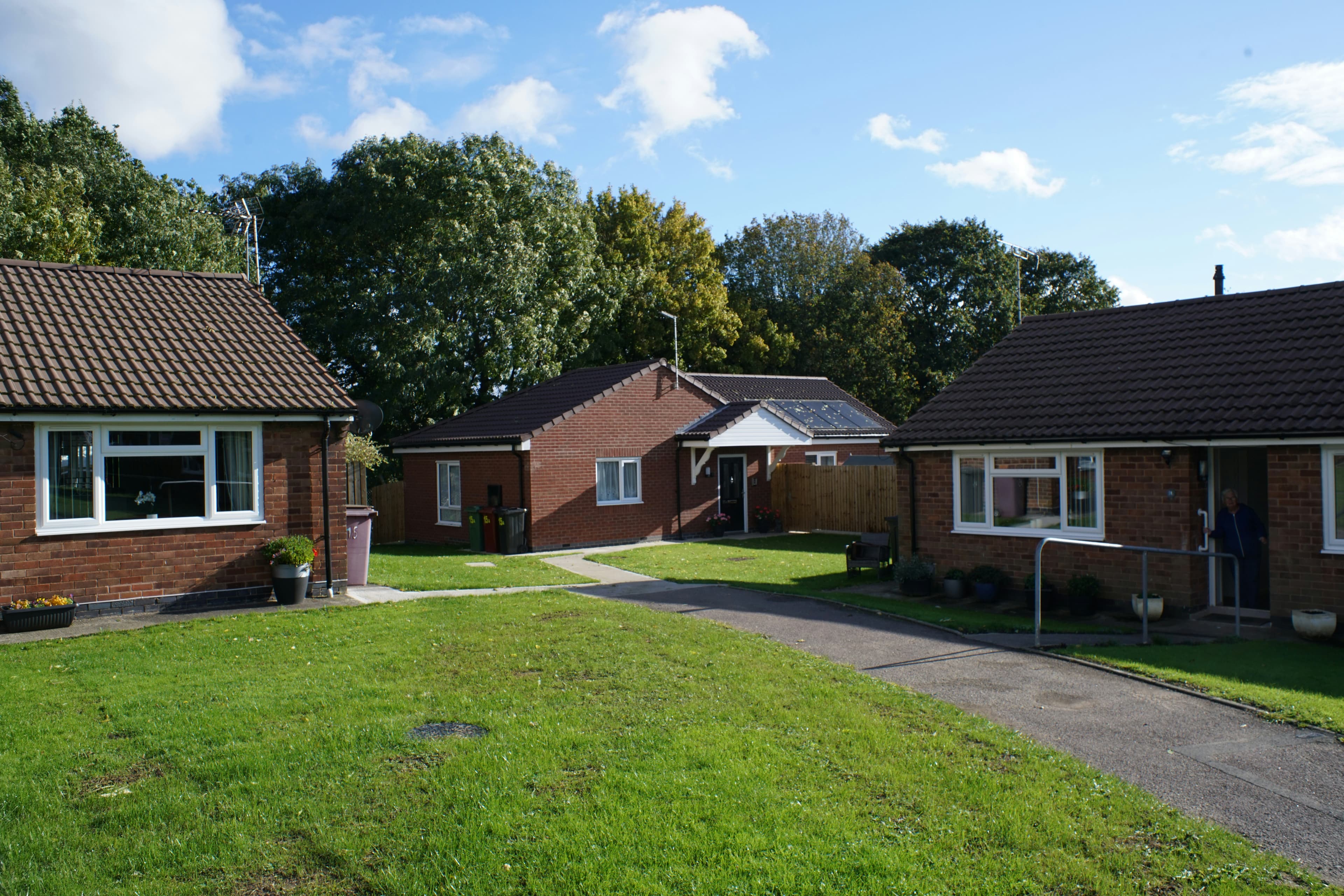 Brick bungalows with green lawns and trees on a residential street