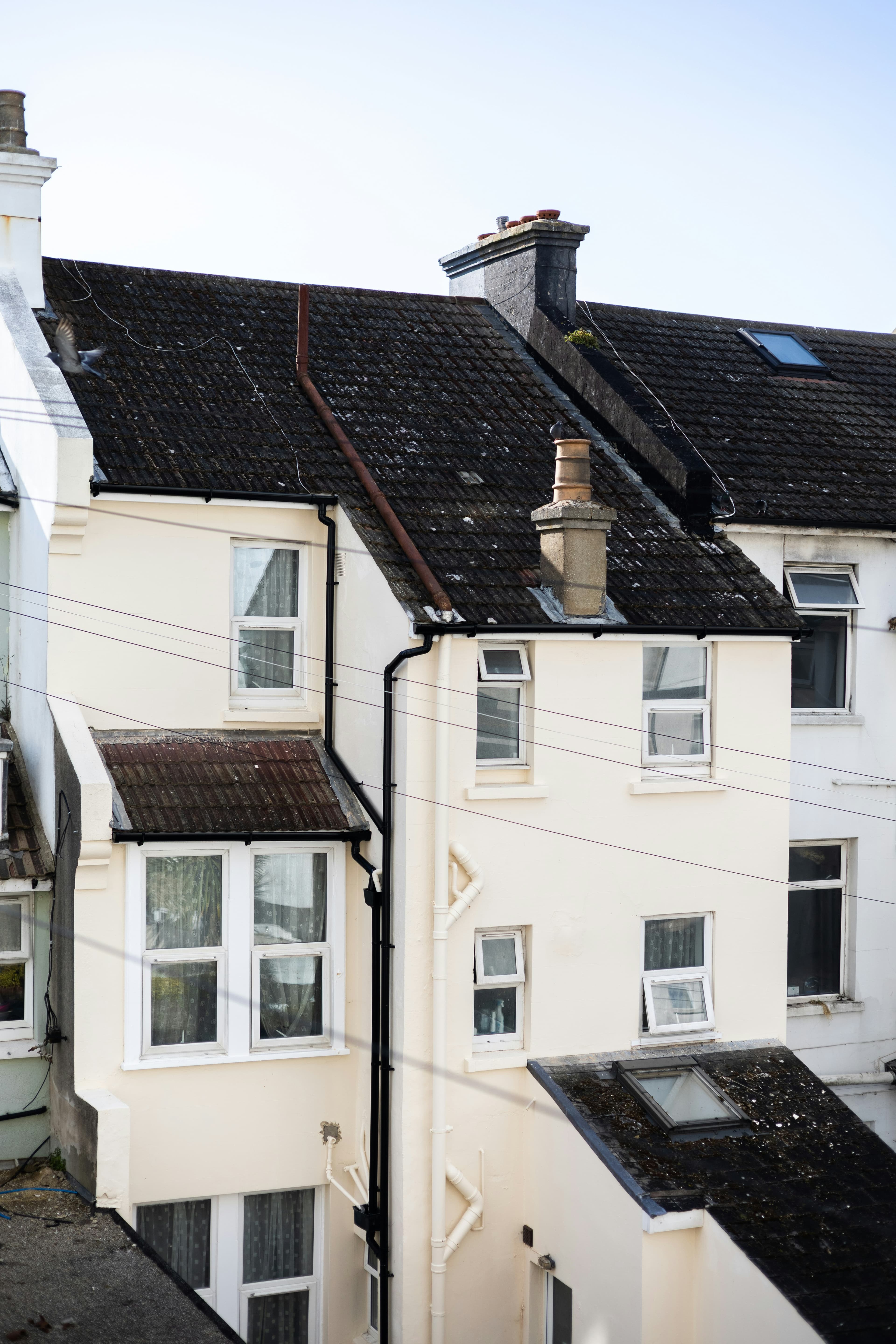 A row of cream-coloured terraced houses with dark tiled roofs and white window frames
