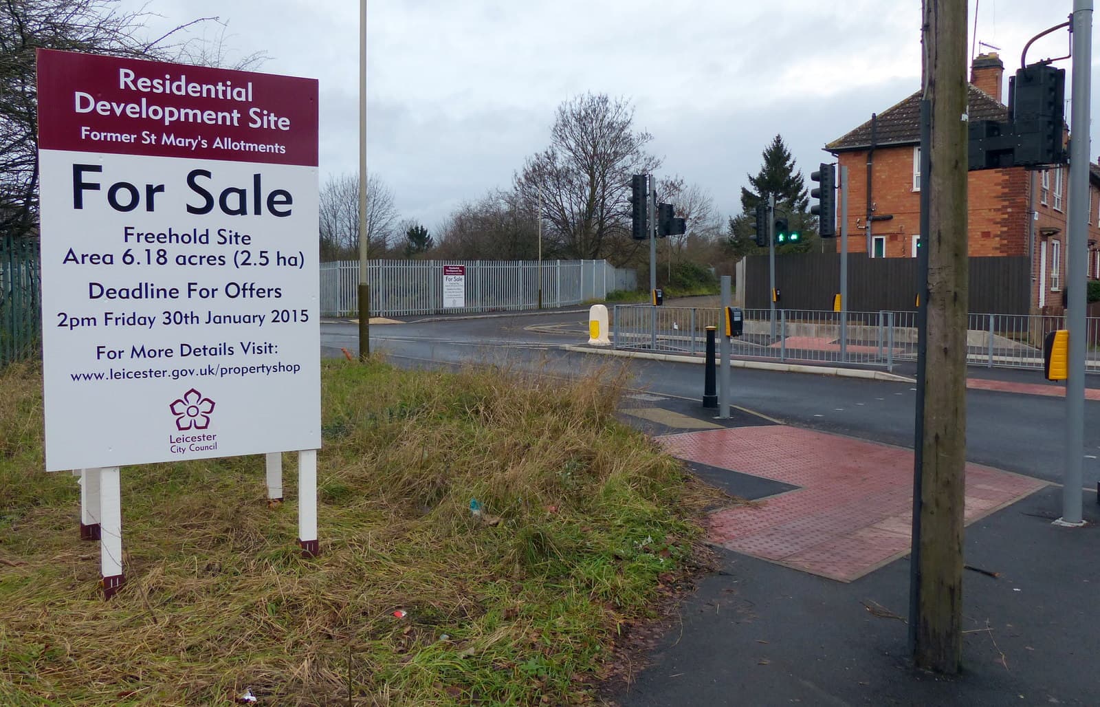 A property for sale sign standing outside a house beside a road in England