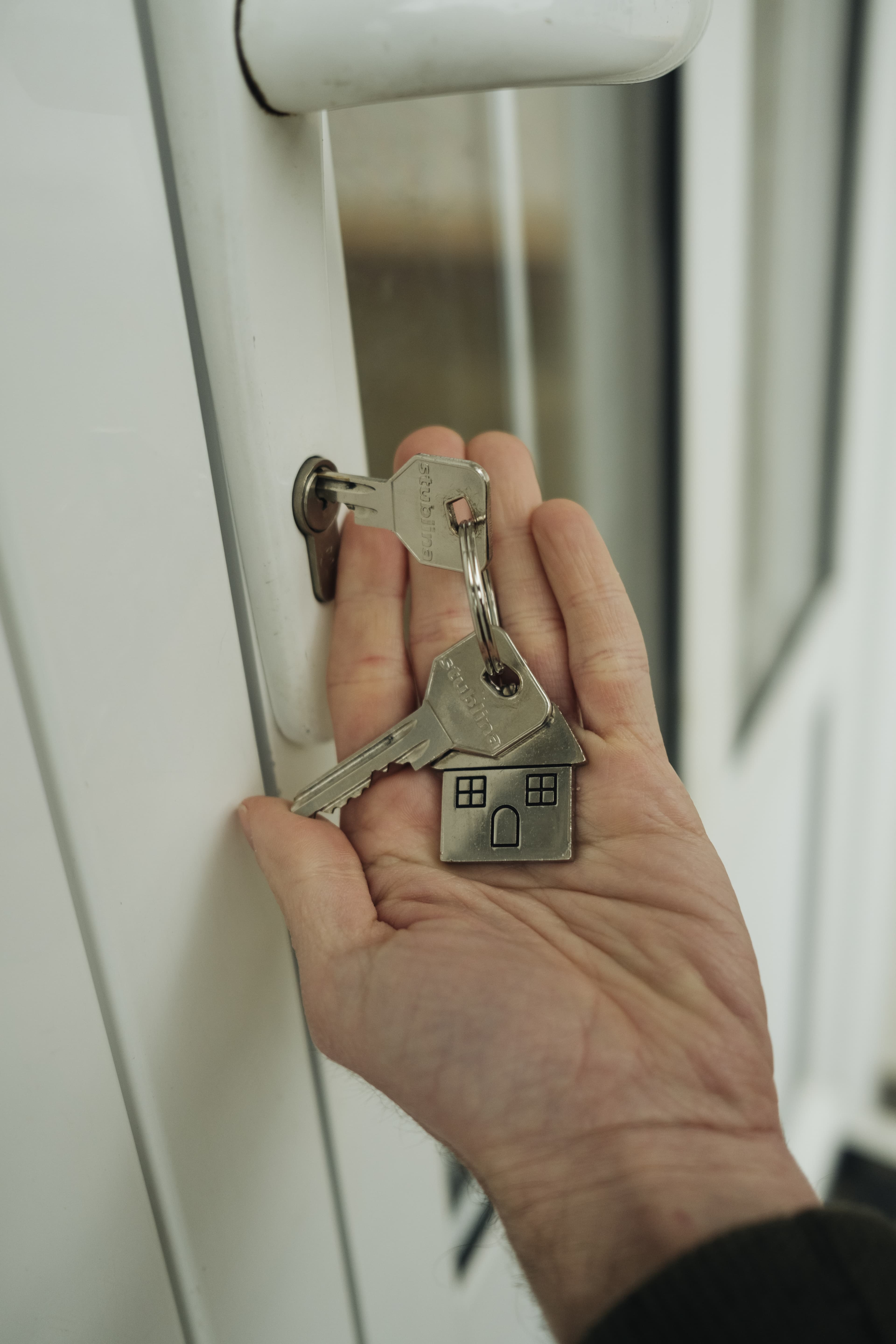 A hand holding house keys beside a front door lock, standing for the conveyancing stage between an accepted offer and completion