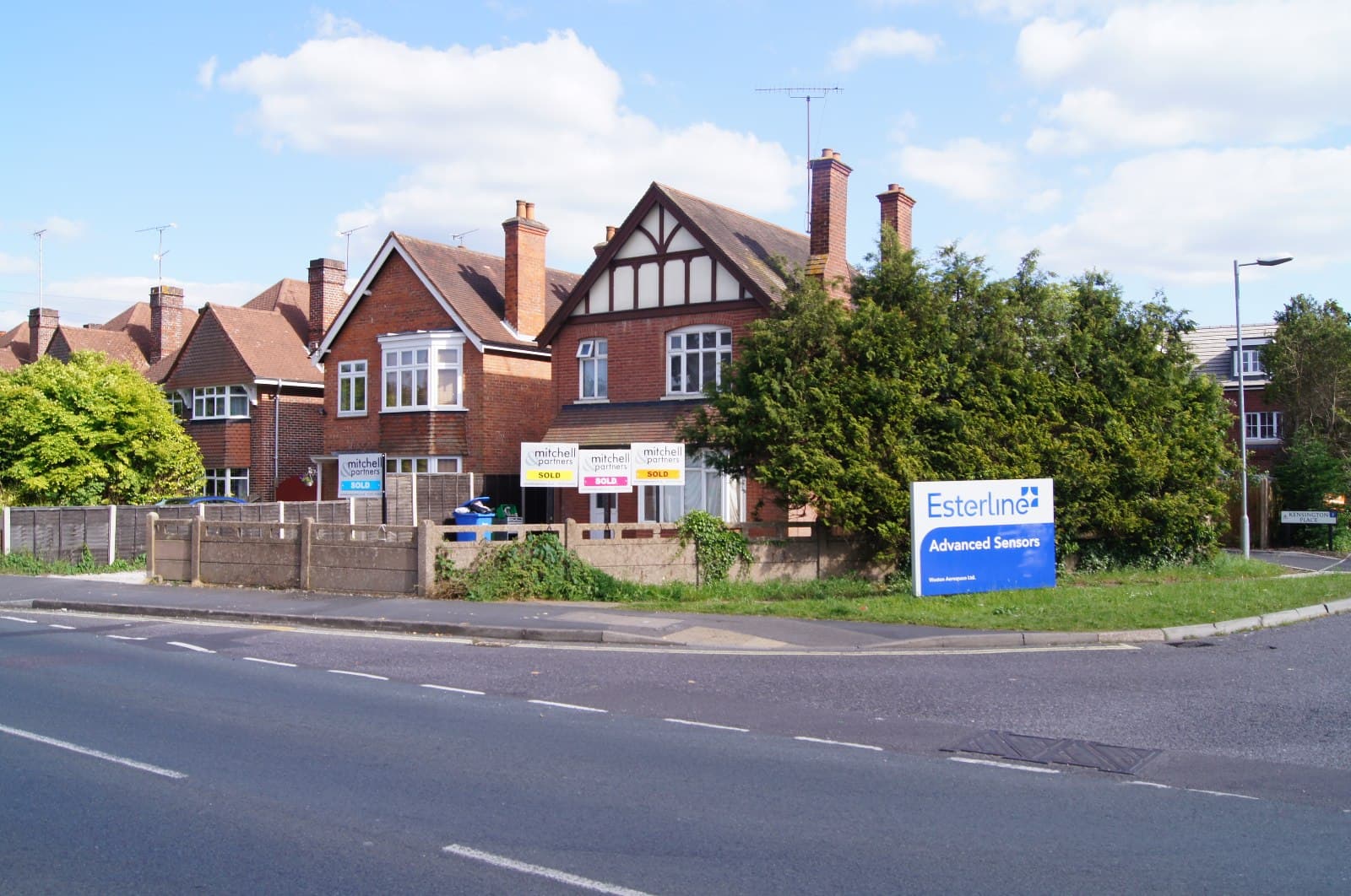 Two estate agent sold boards outside terraced houses on a residential street in England.