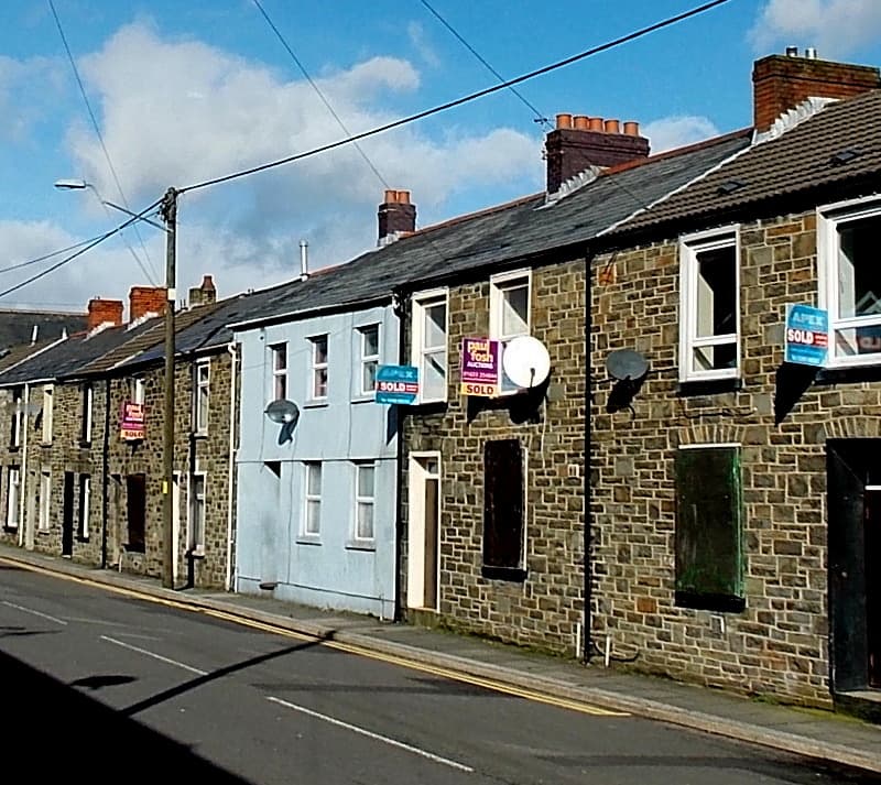 Estate agent Sold boards outside a row of terraced houses on a residential street