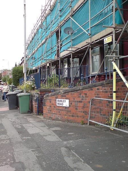 Scaffolding erected across the front of a row of brick terraced houses undergoing repairs