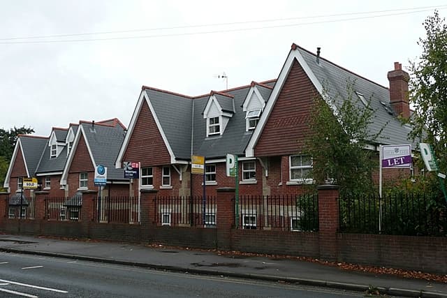 A three-storey block of red brick flats on a residential road in England