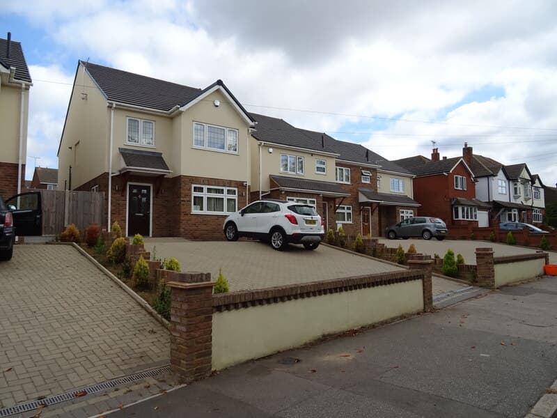A row of individually built detached and semi-detached houses with block-paved front drives on London Road, Basildon, Essex