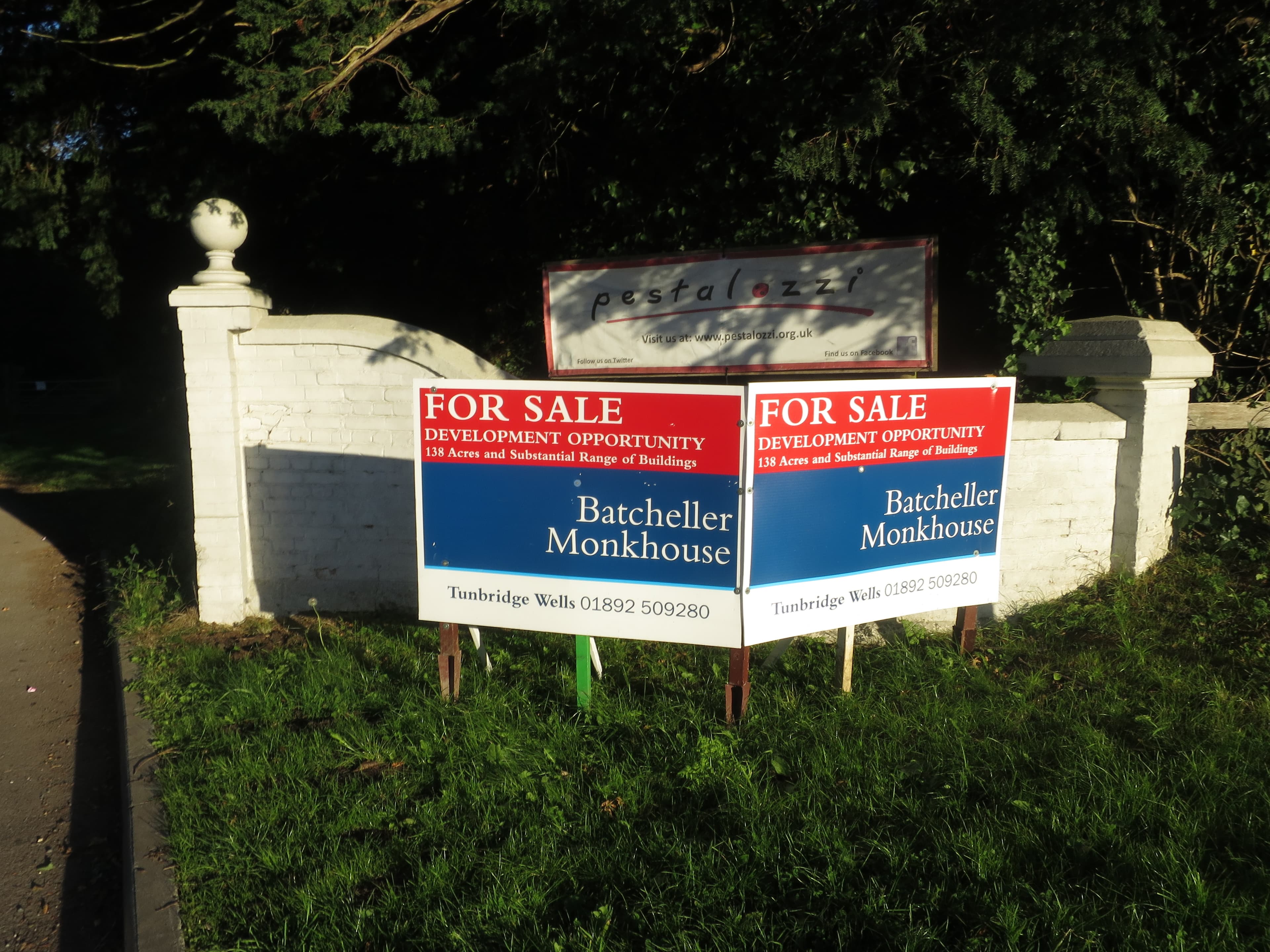 Several estate agent for sale boards standing together at the entrance to a residential road in England.