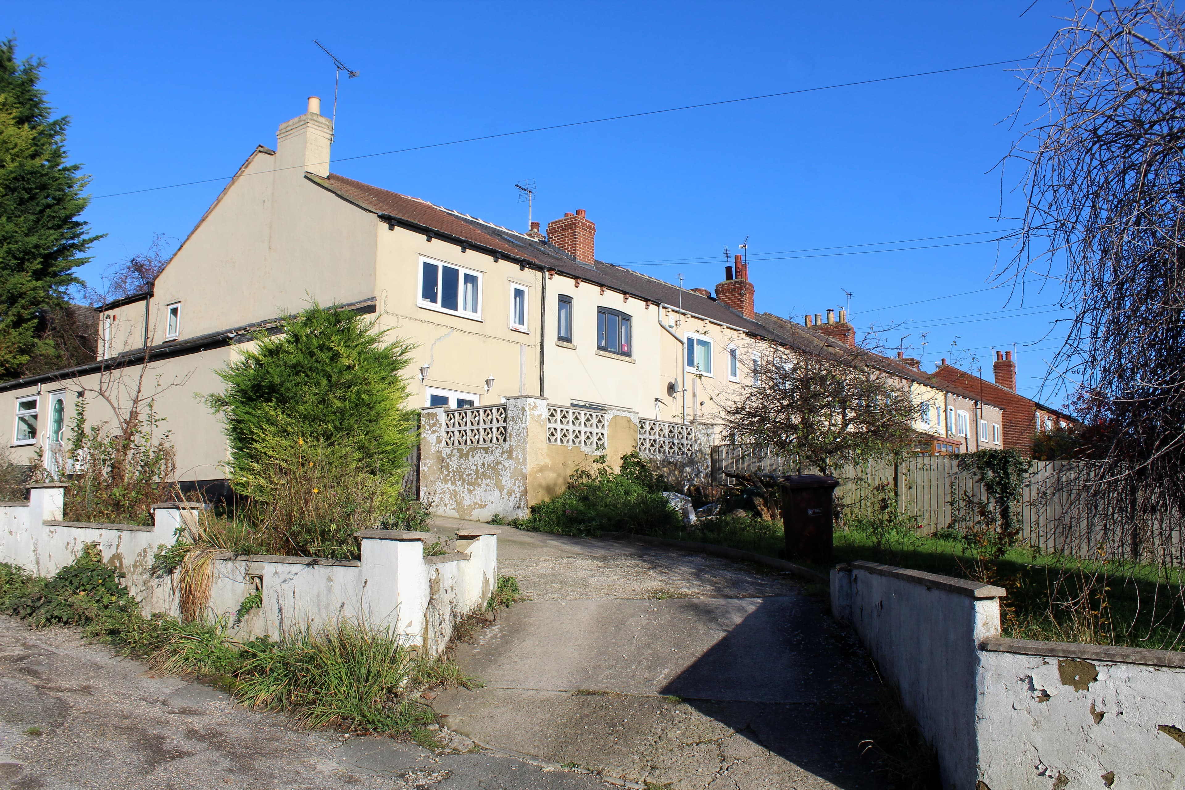 A long row of red brick terraced houses running along a residential road
