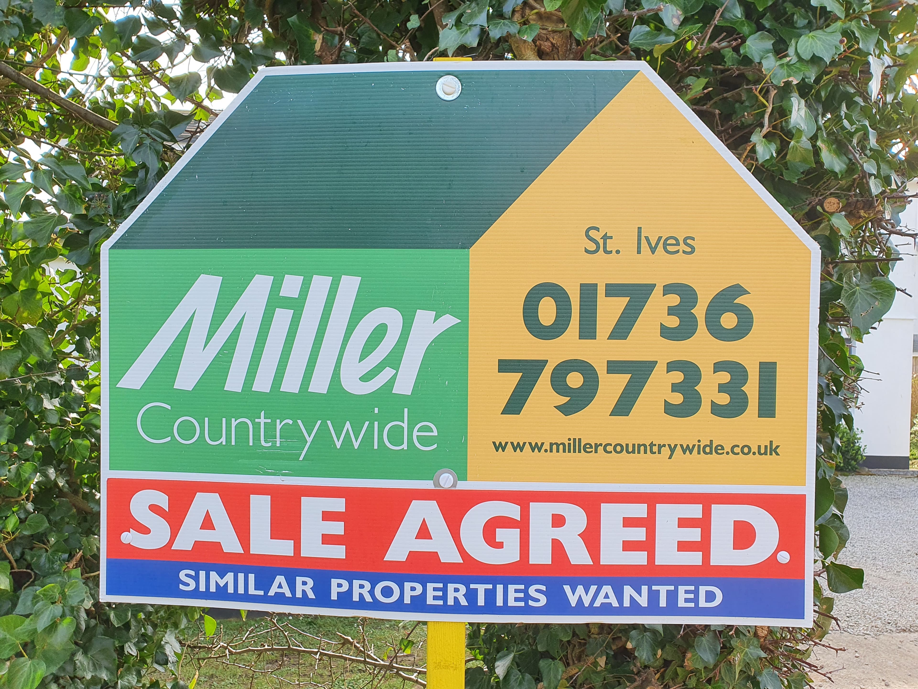 A UK estate agent for-sale sign outside a home, the point at which sellers choose which agent to trust.