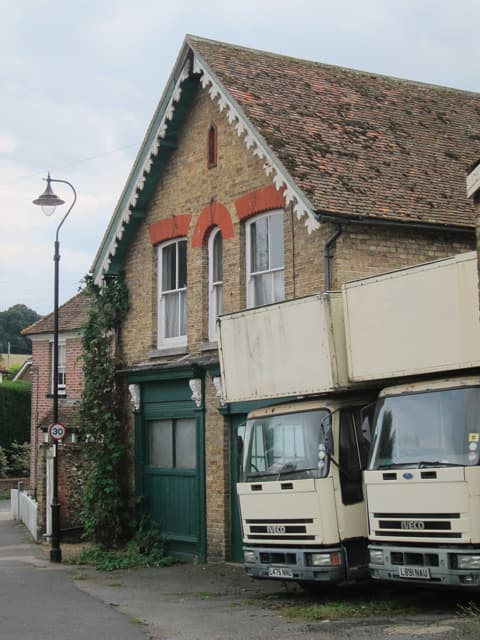 Two removals lorries parked on a residential road beside a hedge