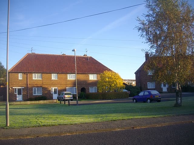 A short row of small terraced houses on a residential crescent, typical first-home stock