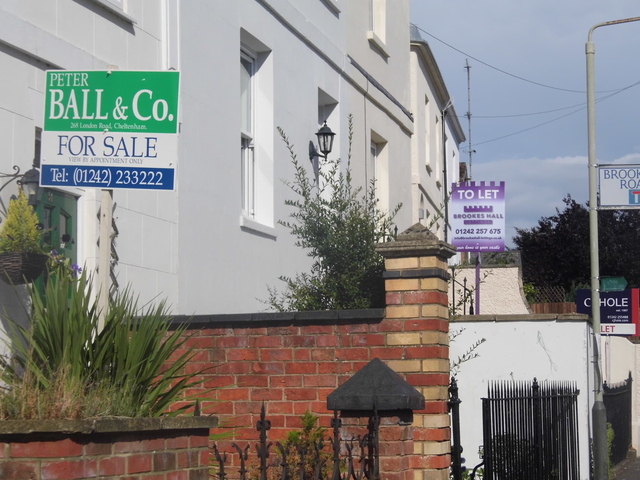 A row of estate agent for sale boards outside houses on a residential street