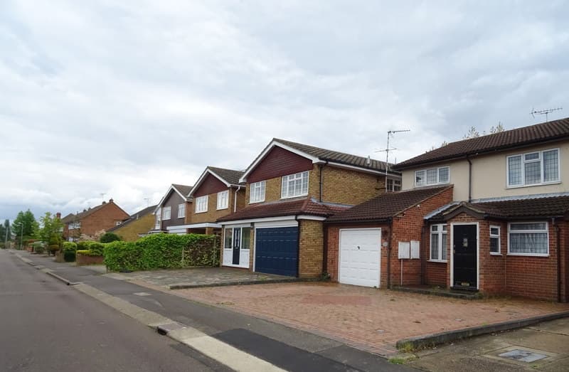 A row of brick houses with block-paved front drives and garages on Worthing Road in Laindon, Basildon, under a cloudy sky