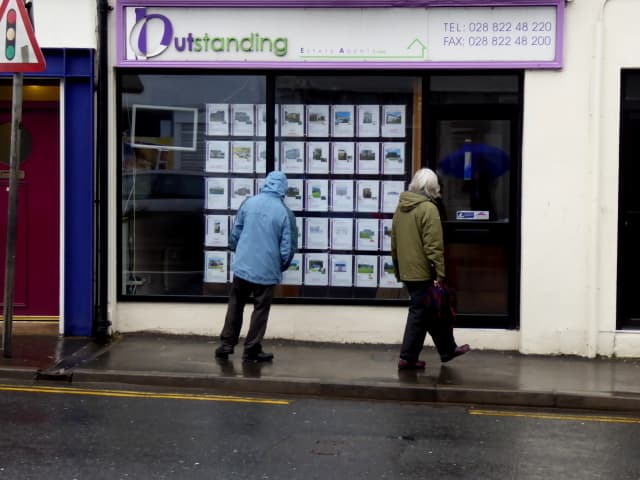 An estate agent's shop window displaying printed property listings on a high street.