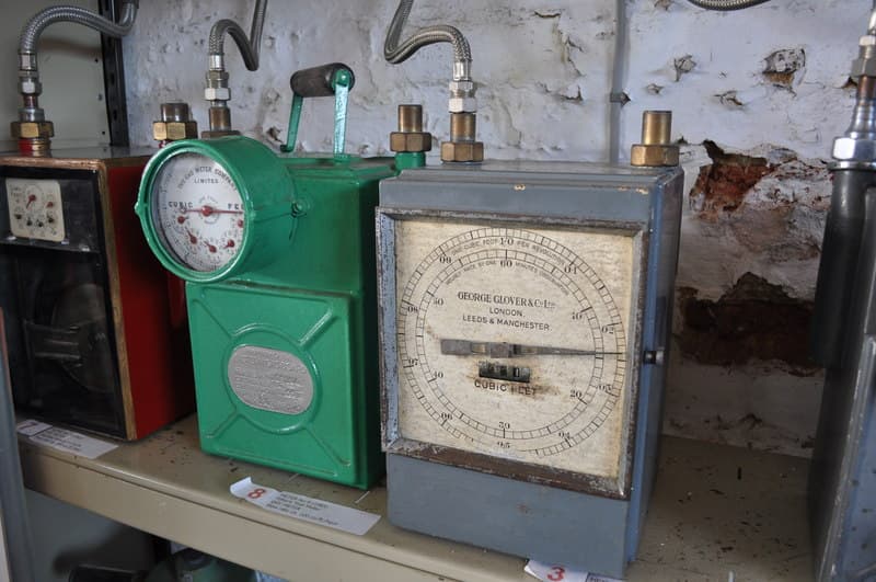 A row of domestic gas meters mounted on an exterior wall of a UK building