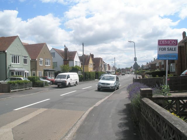 A house for sale sign standing on a residential street in the UK