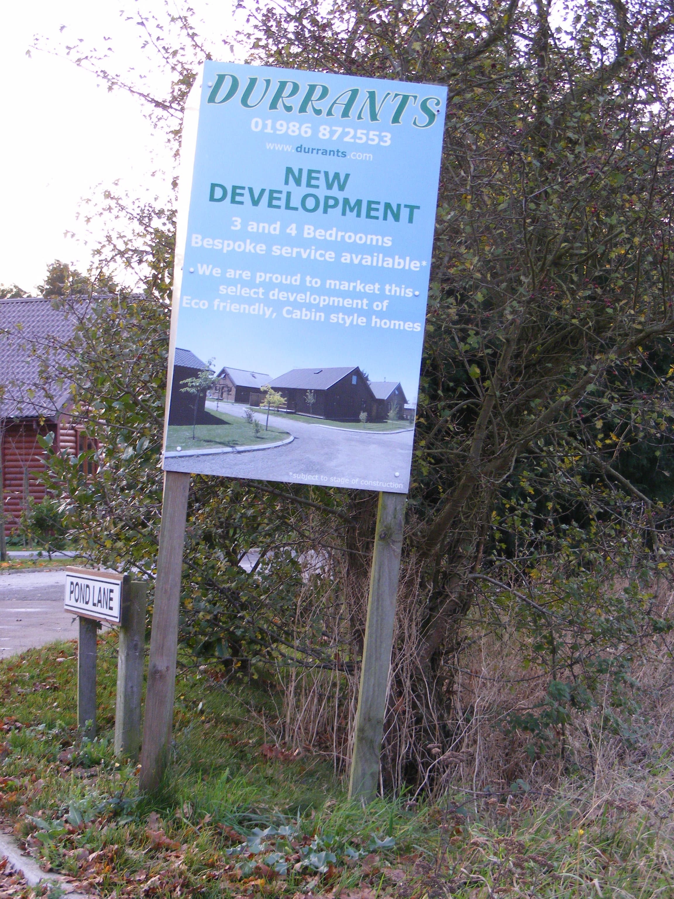An estate agent's For Sale board fixed to a post outside a house
