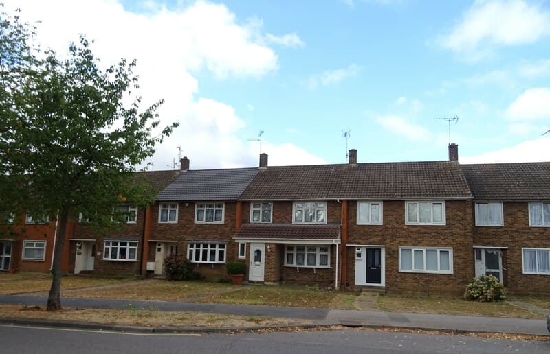 A terrace of brick houses with bay windows on Clay Hill Road in Basildon, Essex, seen from across the road