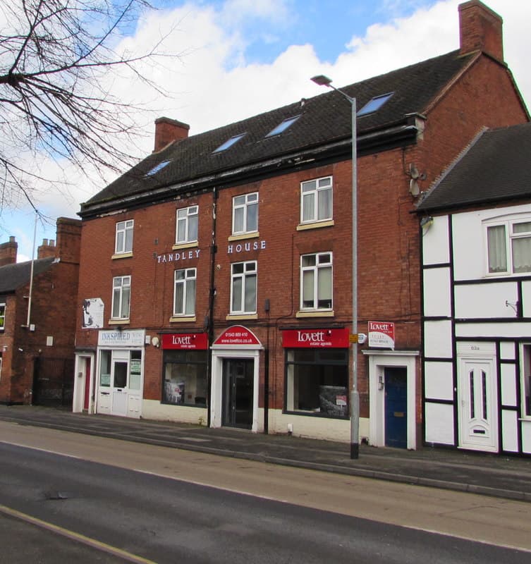 A high street estate agency office with property listings displayed in the window