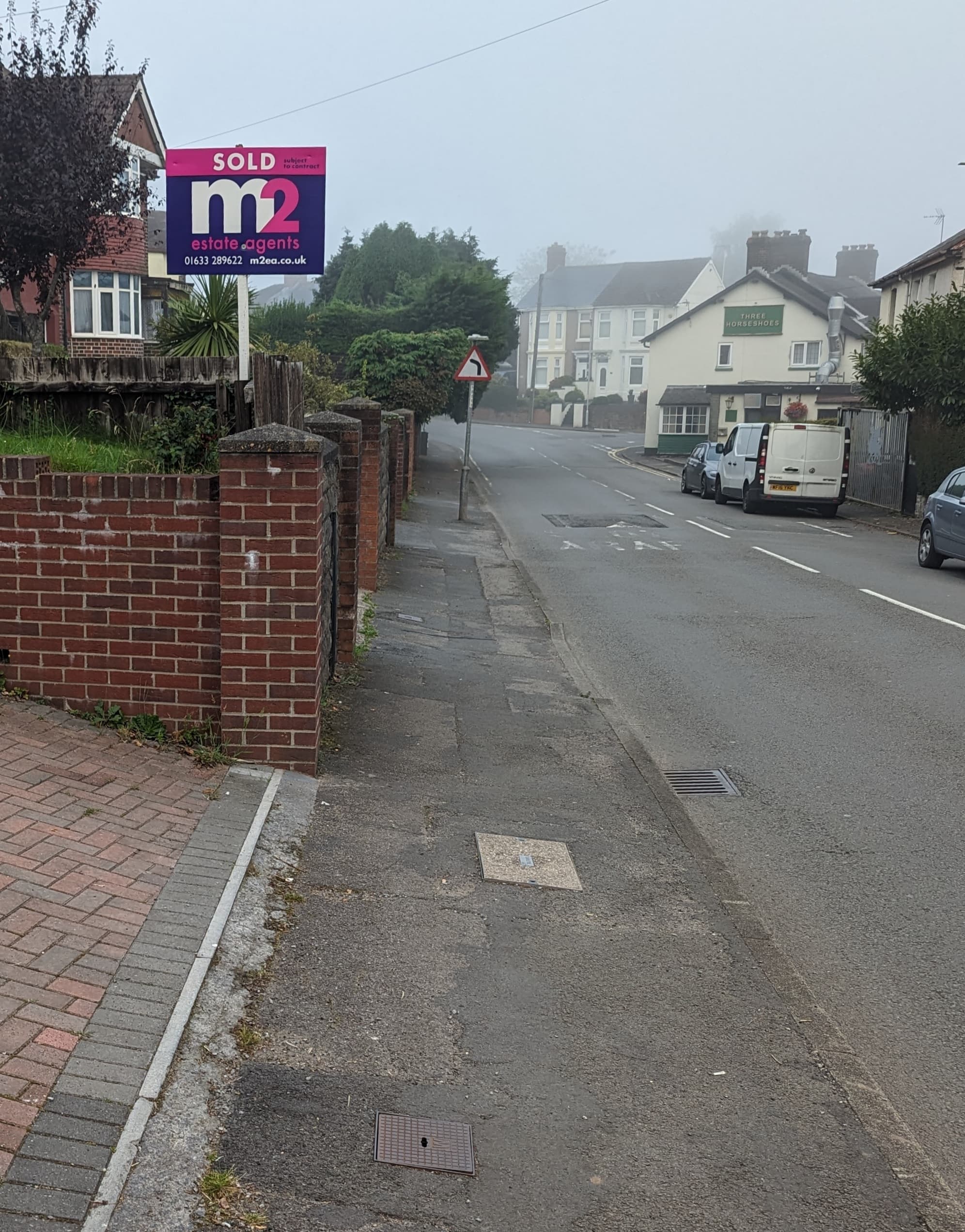 An estate agent's Sold board outside a house on a residential road