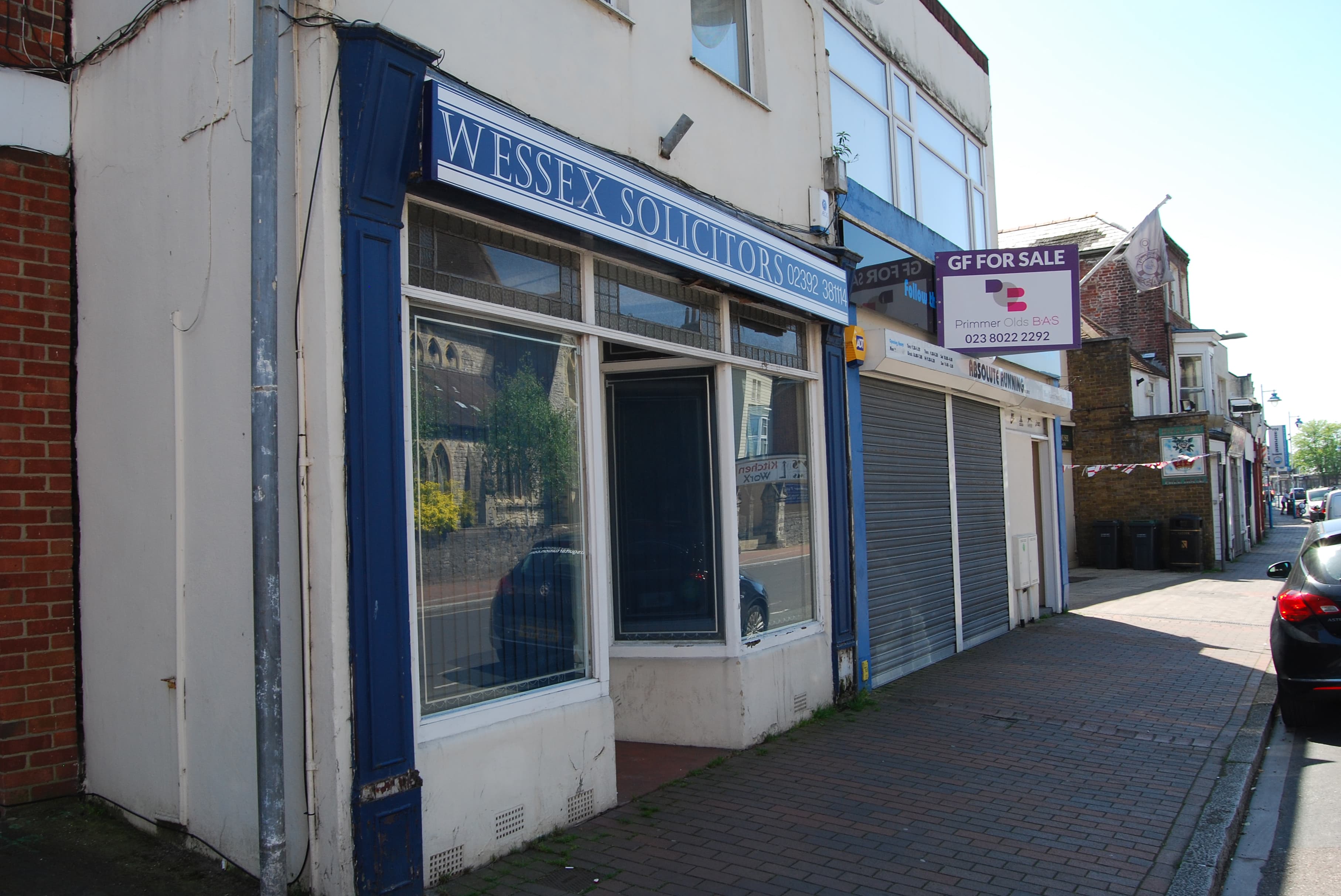 The frontage of a high street solicitors office with a signboard above the window